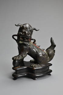 A CHINESE LACQUERED BRONZE MODEL OF A BUDDHISTIC LION, LATE MING DYNASTY 17TH CENTURY. The figure: A CHINESE LACQUERED BRONZE MODEL OF A BUDDHISTIC LION, LATE MING DYNASTY 17TH CENTURY. The figure seated with traces of black and red lacquer traces on a carved wood stand. 15cm tall on stand.