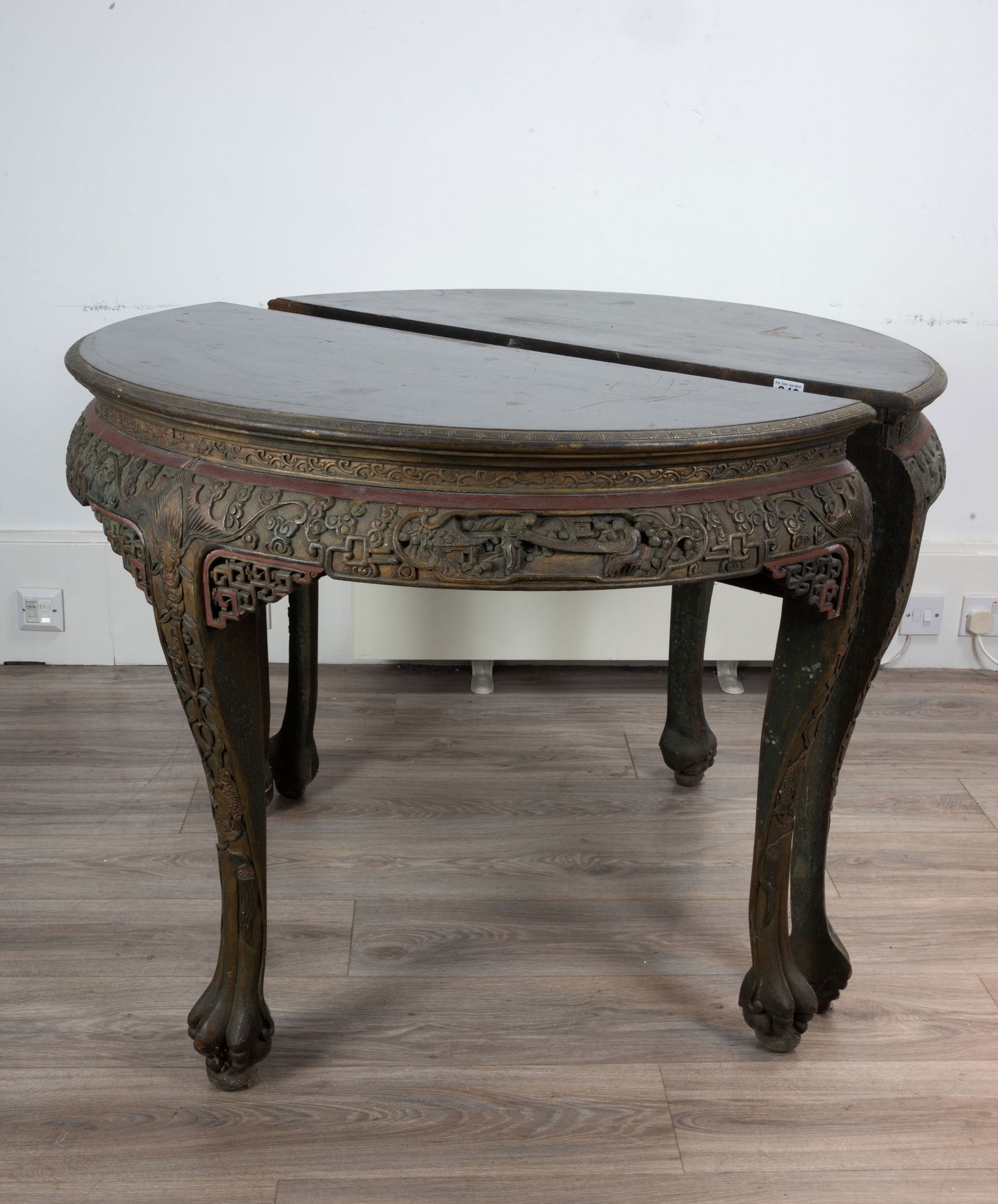 A PAIR OF CHINESE LATE QING DYNASTY BLACK AND RED LACQUER DEMI-LUNE CONSOLE TABLES. Each enriched in: A PAIR OF CHINESE LATE QING DYNASTY BLACK AND RED LACQUER DEMI-LUNE CONSOLE TABLES. Each enriched in gilding and carved with a frieze of figures before pavilions, stylised dragons and fretwork within