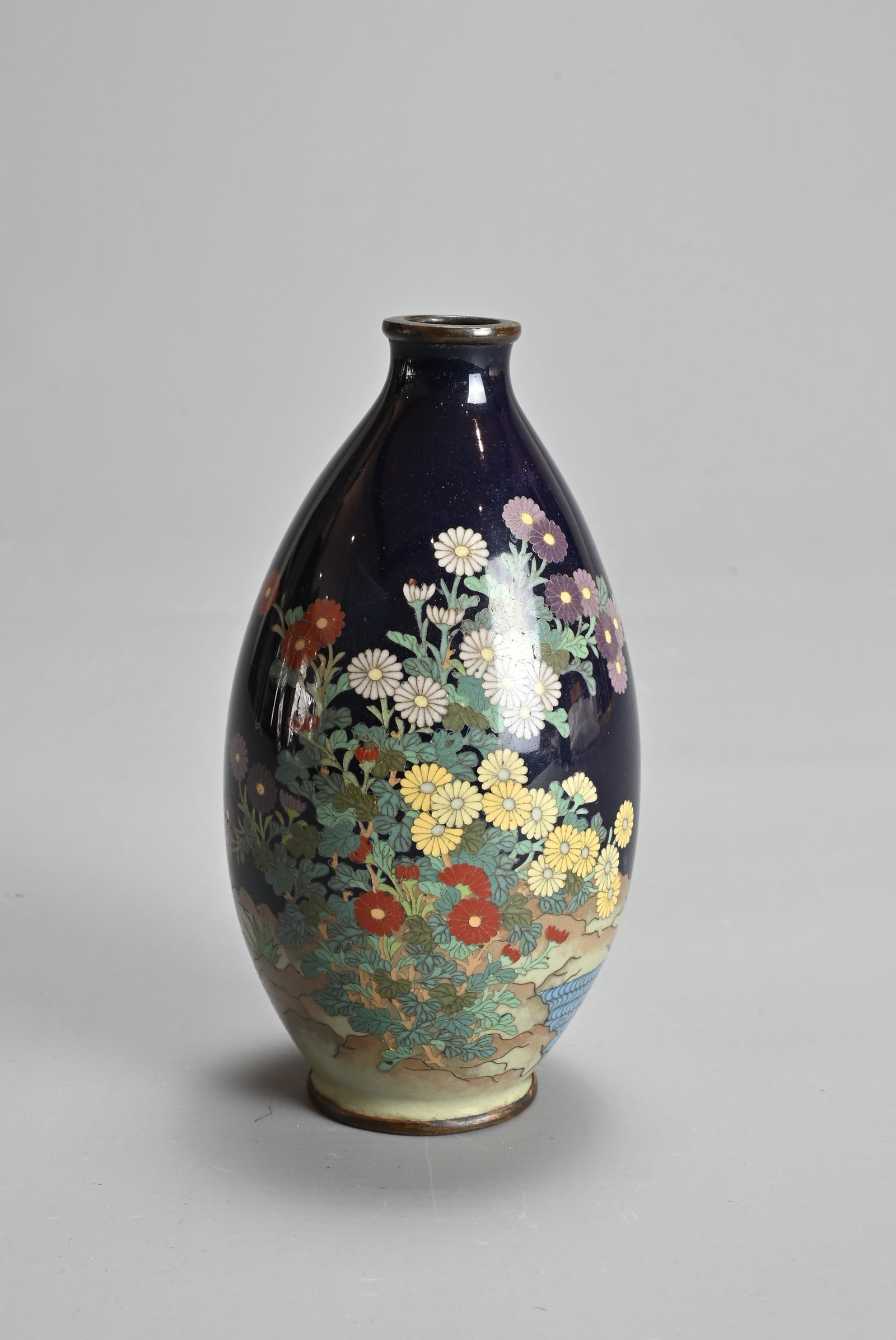 A JAPANESE CLOISONNE ENAMEL VASE, MEIJI PERIOD. Of ovoid form in a dark blue ground decorated with: A JAPANESE CLOISONNE ENAMEL VASE, MEIJI PERIOD. Of ovoid form in a dark blue ground decorated with chrysanthemums. 12.5cm tall.
