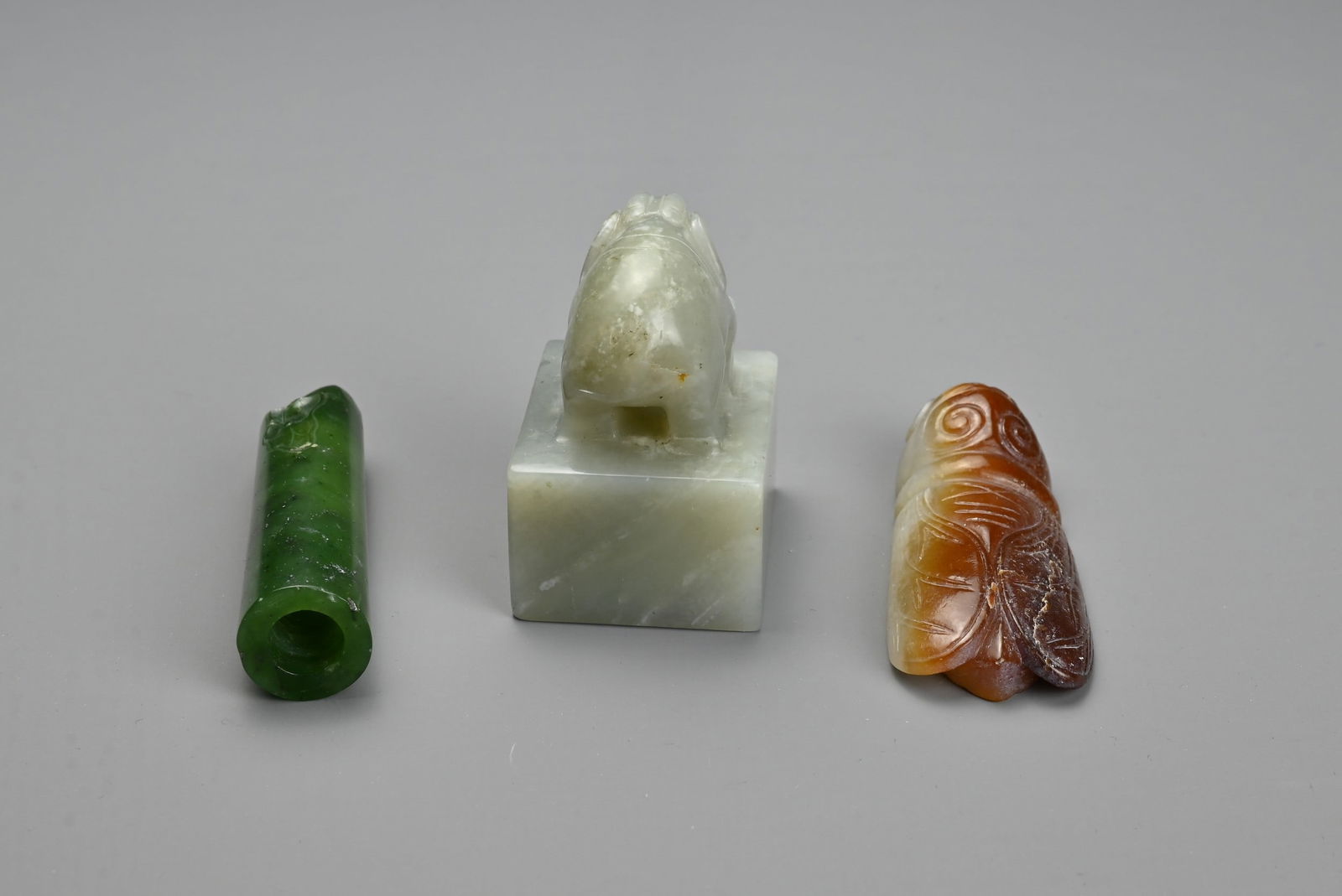 THREE CHINESE CARVED JADE ITEMS. To include a square seal surmounted by an elephant and incised four (1 of 4)