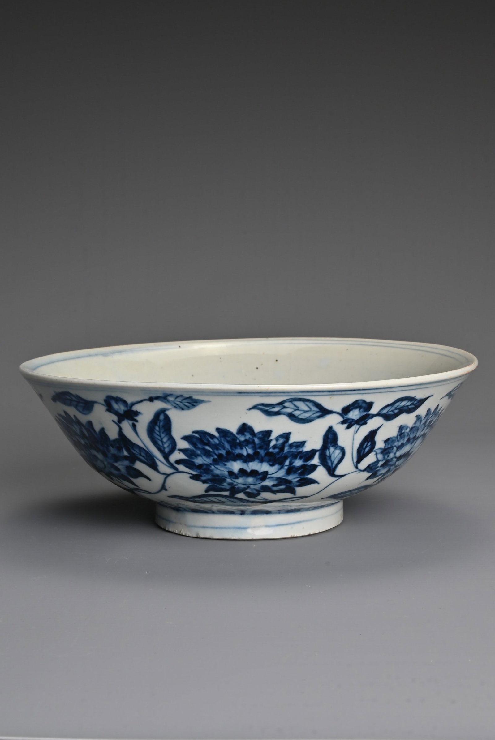 A CHINESE BLUE AND WHITE PORCELAIN BOWL, 18/19TH CENTURY. Heavily potted decorated to the interior: A CHINESE BLUE AND WHITE PORCELAIN BOWL, 18/19TH CENTURY. Heavily potted decorated to the interior with the three friends of winter comprising pine, bamboo, and plum. The exterior with floral decorati