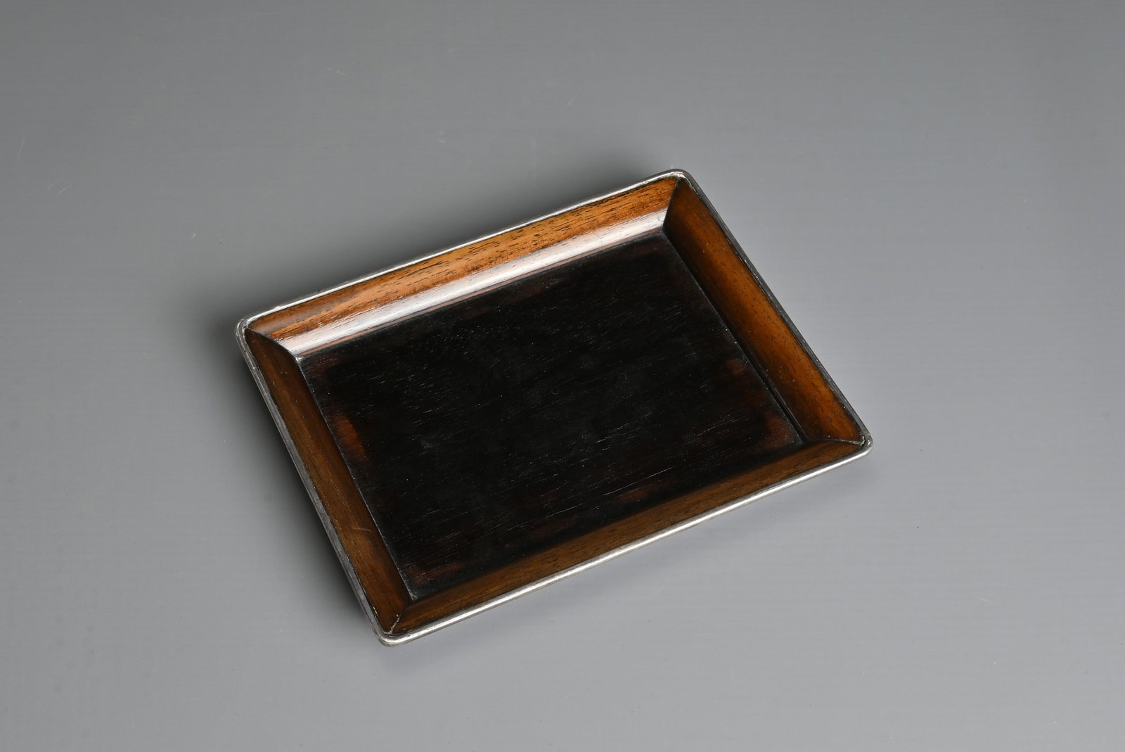 A SMALL JAPANESE HARDWOOD TRAY WITH WHITE METAL RIM, 20TH CENTURY. Of rectangular form with white (1 of 3)
