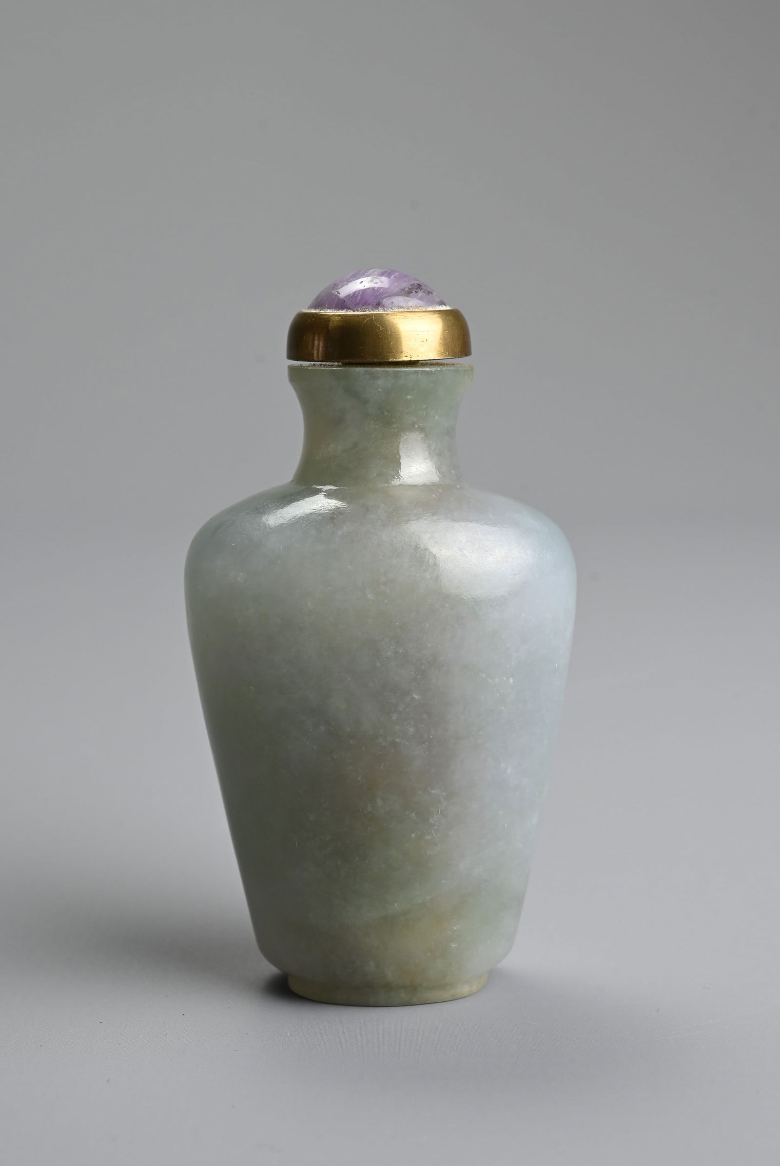 A CHINESE CARVED JADE SNUFF BOTTLE, QING DYNASTY. The jade green with patches of pale purple, of (1 of 6)