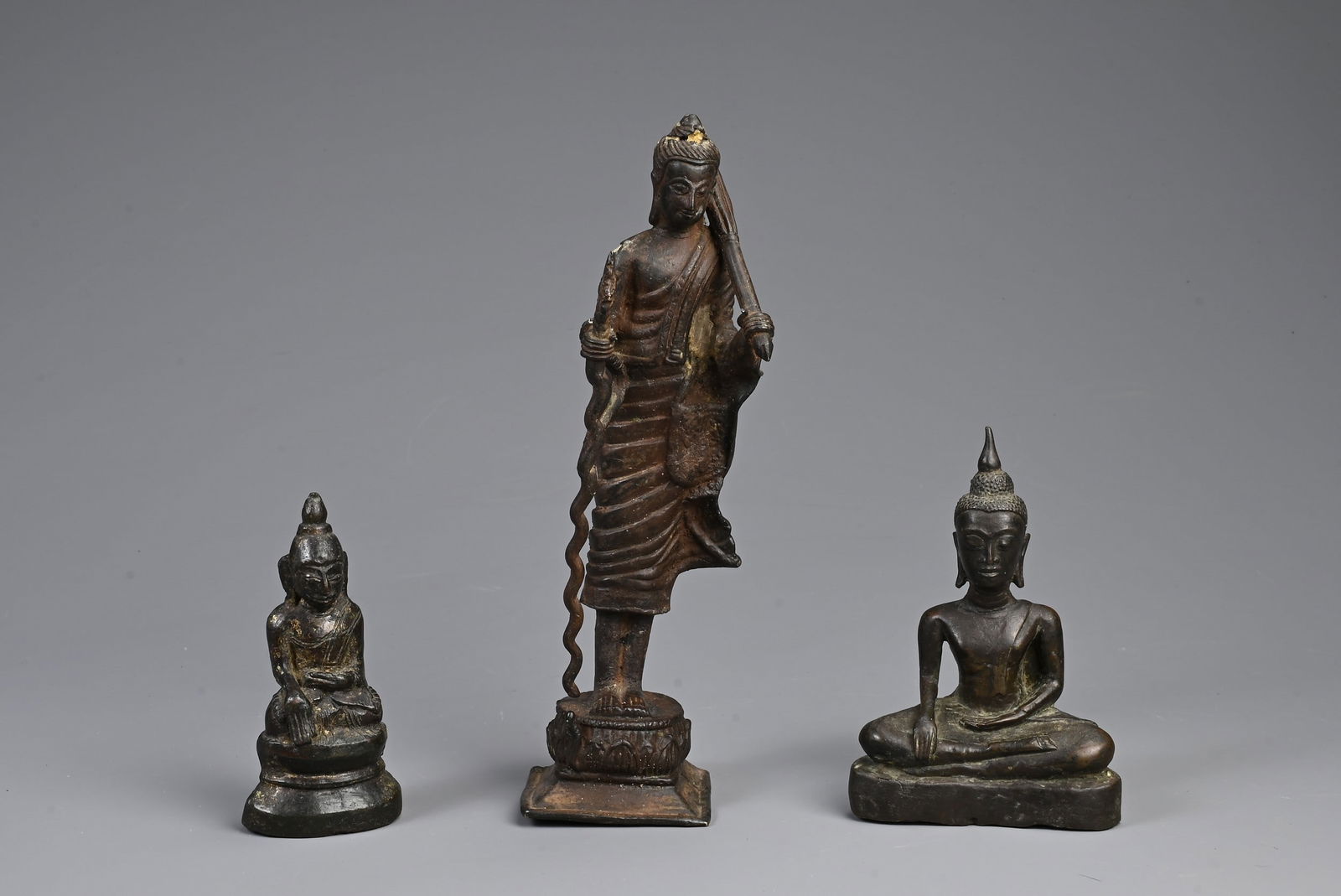 THREE SOUTH EAST ASIAN BRONZE MODELS OF BUDDHAS. Comprising: a buddha Shakyamuni, Laos, seated in (1 of 5)
