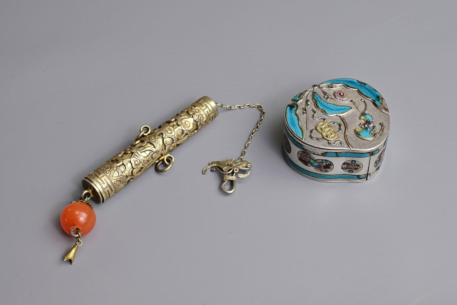 A CHINESE SILVER AND ENAMEL PILL BOX WITH GILT NEEDLE CASE, 19//20TH CENTURY. The silver box of: A CHINESE SILVER AND ENAMEL PILL BOX WITH GILT NEEDLE CASE, 19//20TH CENTURY. The silver box of peach form decorated with a bat and leaves with floral roundels, stamped to base; Together with a gilt p