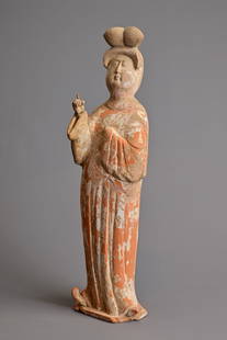 A CHINESE PAINTED POTTERY FIGURE OF COURT LADY, TANG DYNASTY (AD 618-907). Modelled standing wearing: A CHINESE PAINTED POTTERY FIGURE OF COURT LADY, TANG DYNASTY (AD 618-907). Modelled standing wearing a long flowing robe, her coiffured hair high on her head, her right hand and index figure pointing