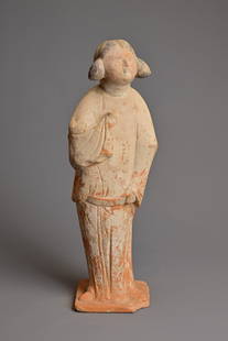 A CHINESE PAINTED POTTERY FIGURE OF COURT LADY, TANG DYNASTY (AD 618-907). Modelled standing wearing: A CHINESE PAINTED POTTERY FIGURE OF COURT LADY, TANG DYNASTY (AD 618-907). Modelled standing wearing a long flowing robe, her coiffured hair and features picked out in black, her arms clasped to her c