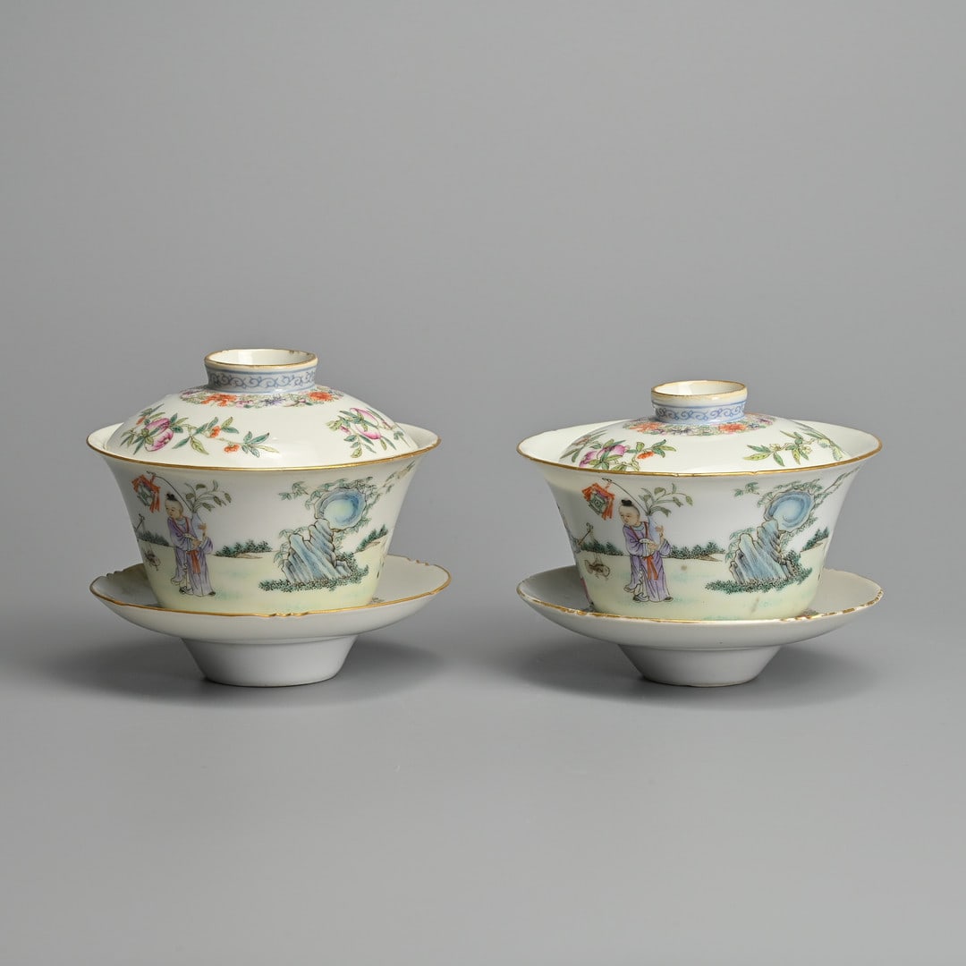 A PAIR OF CHINESE FAMILLE ROSE PORCELAIN TEA CUPS AND COVERS ON STANDS, LIN ZHI CHENG XIANG MARKS,: Finely painted featuring boys holding ornaments with rams in landscape scene. The covers decorated with Sanduo, 'The Three Abundances' of peach pomegranate and finger citron. The stands with a band of