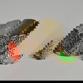 A GROUP OF CHINESE WHITE METAL, SILVER, JADEITE AND CORAL MOUNTED JEWELLERY, EARLY 20TH CENTURY.: Comprising a Chinese white metal bracelet, with eight pierced gilt panels of ladies before flowering and fruiting trees, stamped CHINA, 18 cm long inc. clasp, weight 33.7 grams; A Chinese silver ring