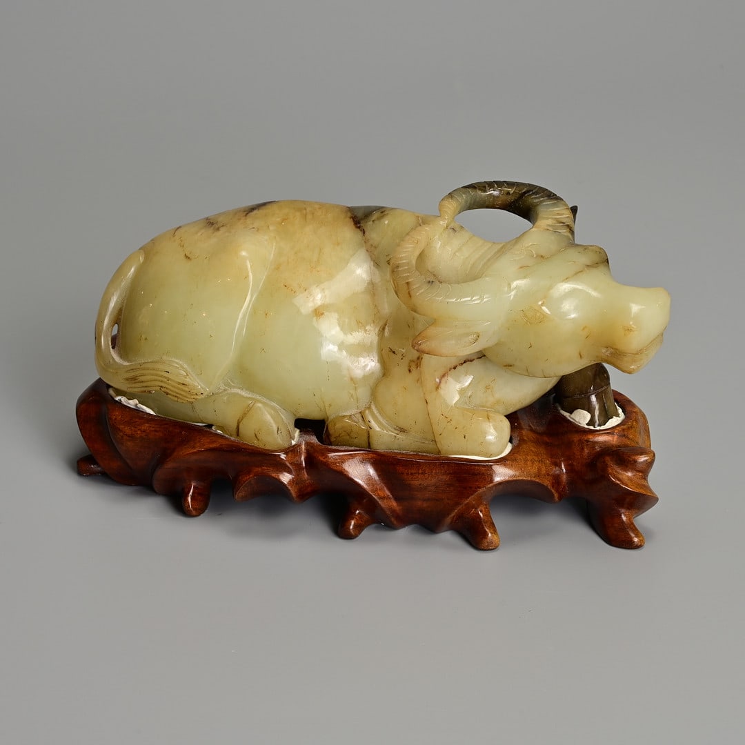 A LARGE CHINESE PALE CELADON AND BROWN JADE CARVING OF A RECUMBENT BUFFALO ON WOODEN STAND, 20TH (1 of 7)