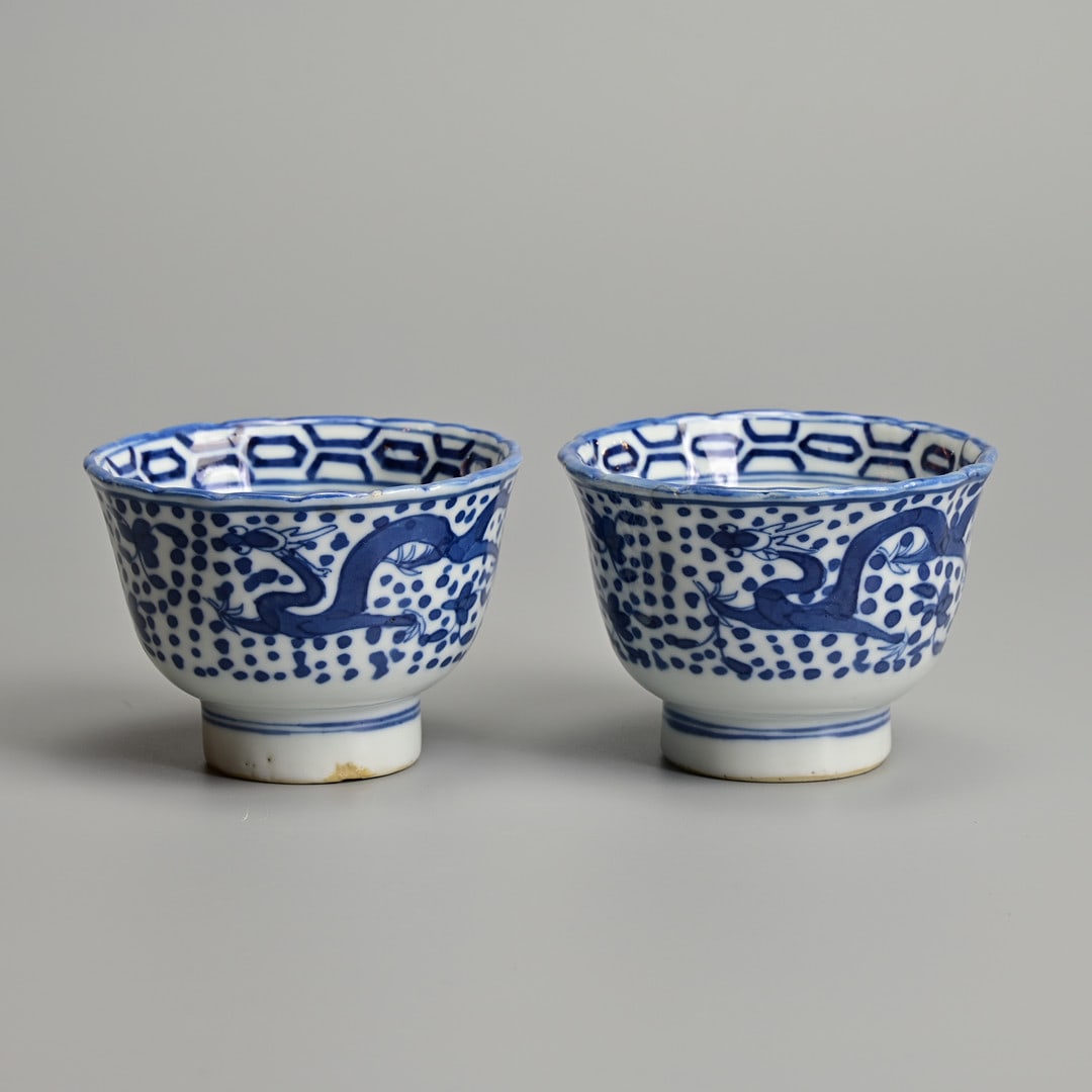 A PAIR OF CHINESE BLUE AND WHITE PORCELAIN TEABOWLS MADE FOR THE VIETNAMESE MARKET, MID-19TH: Each painted to the well with a pelican or swan, below a band of hexagonal ornament, the exterior with dragons and scattered flowers on a dot pattern ground, below shaped rim. 8.5cm diam. (2).