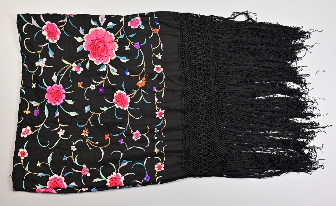 A CHINESE BLACK EMBROIDERED SILK SHAWL, EARLY 20TH CENTURY.: Embroidered with pink and blue flowers, within fringed tasselled borders, 152cm x 132 cm exc. tassels.