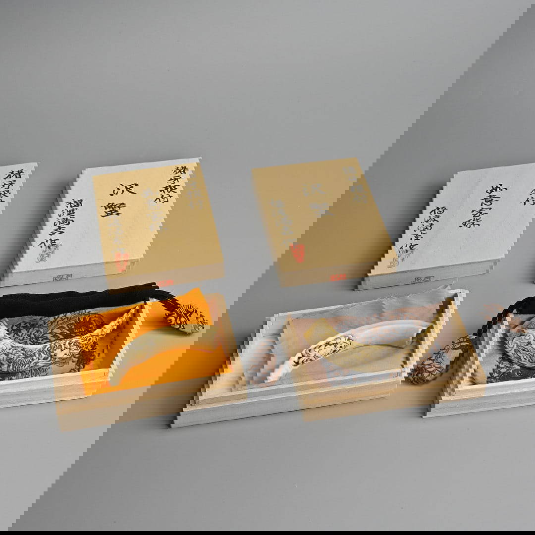 TWO CONTEMPORARY JAPANESE CARVED BOAR (IWAMI) TUSK NETSUKES, IN ORIGINAL BOXES.