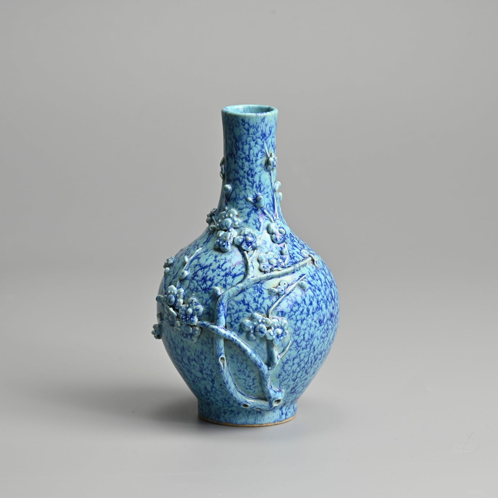 A CHINESE ROBIN'S EGG GLAZE PORCELAIN BOTTLE VASE, 19TH CENTURY.: A CHINESE ROBIN'S EGG GLAZE PORCELAIN BOTTLE VASE, 19TH CENTURY. Moulded decoration in relief to the body featuring a flowering prunus branch, covered in a turquoise-blue glaze with purple streaks. 14