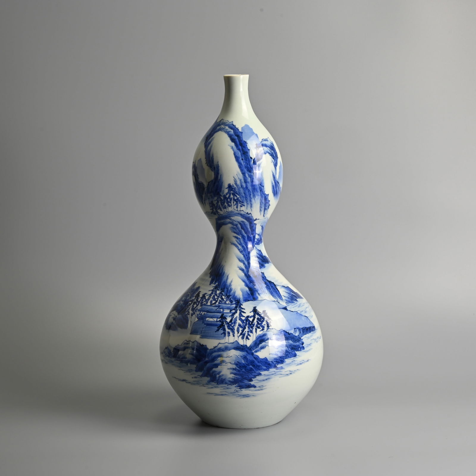 A LARGE CHINESE BLUE AND WHITE PORCELAIN DOUBLE GOURD 'LANDSCAPE' VASE, 20TH CENTURY.: A LARGE CHINESE BLUE AND WHITE PORCELAIN DOUBLE GOURD 'LANDSCAPE' VASE, 20TH CENTURY. Of slender form decorated with buildings in a mountainous landscape scene. 50cm tall. Condition: In good overall c