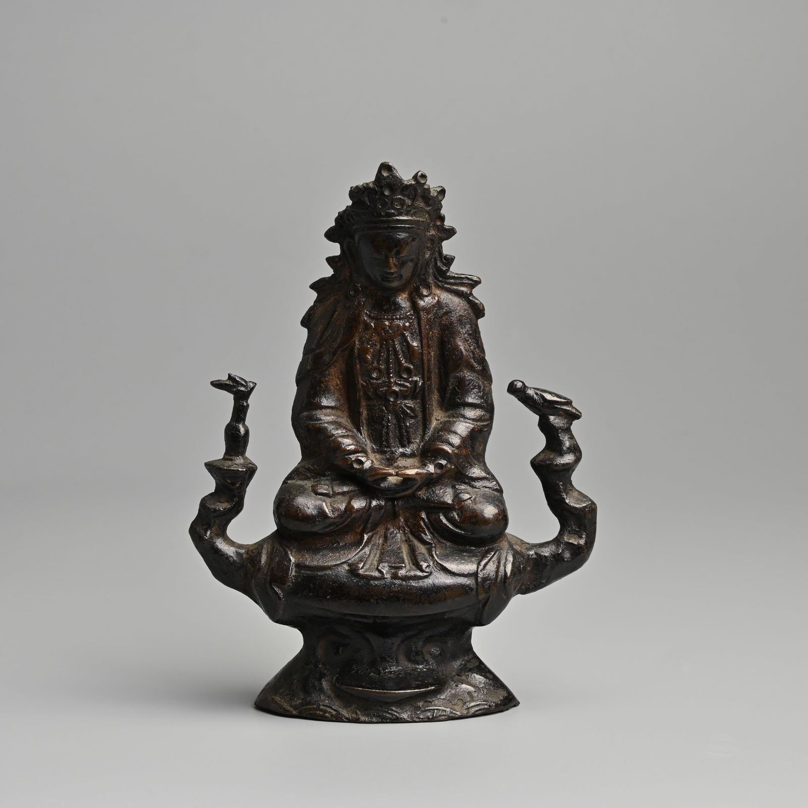 A CHINESE BRONZE OF A BODHISATTVA, 17/18TH CENTURY.: A CHINESE BRONZE OF A BODHISATTVA, 17/18TH CENTURY. Seated on a rockwork pedestal flanked by a bird and bottle, dressed in robes tied at the waist with jewelled necklace and headdress. 17cm tall. Cond
