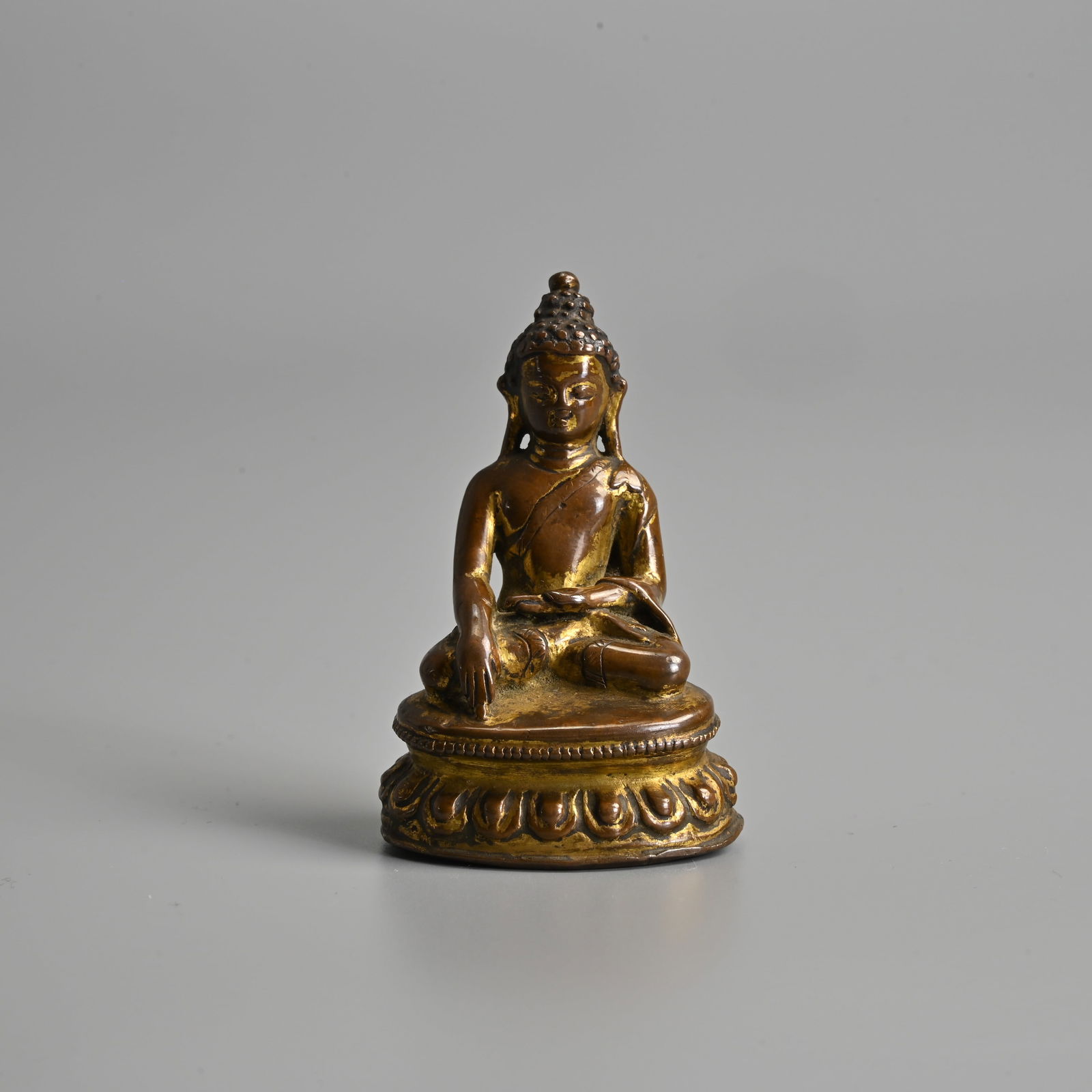 A SMALL TIBETAN GILT COPPER ALLOY FIGURE OF BUDDHA, CIRCA 17TH CENTURY.: A SMALL TIBETAN GILT COPPER ALLOY FIGURE OF BUDDHA, CIRCA 17TH CENTURY. Figure of Shakyamuni seated in meditation on a lotus base wearing a dhoti draping over the left shoulder. 6.2cm tall. Weight 92