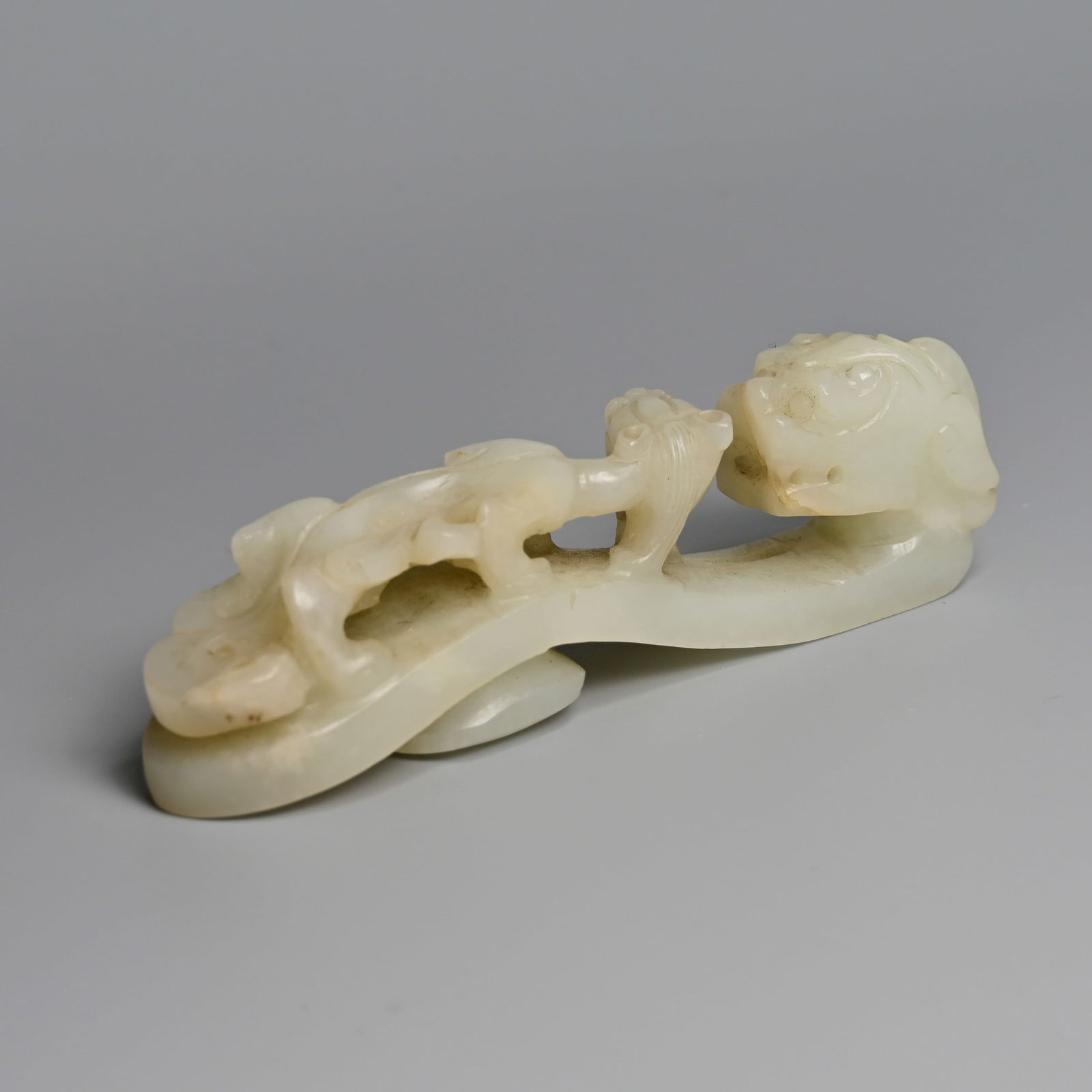 A CHINESE WHITE JADE BELT HOOK, LATE QING DYNASTY.: A CHINESE WHITE JADE BELT HOOK, LATE QING DYNASTY. With a dragon head terminal surmounted by an openwork chilong. Weight 61.7 grams. Length 9.5cm. Condition: 2mm defect to the beard of the chilong.