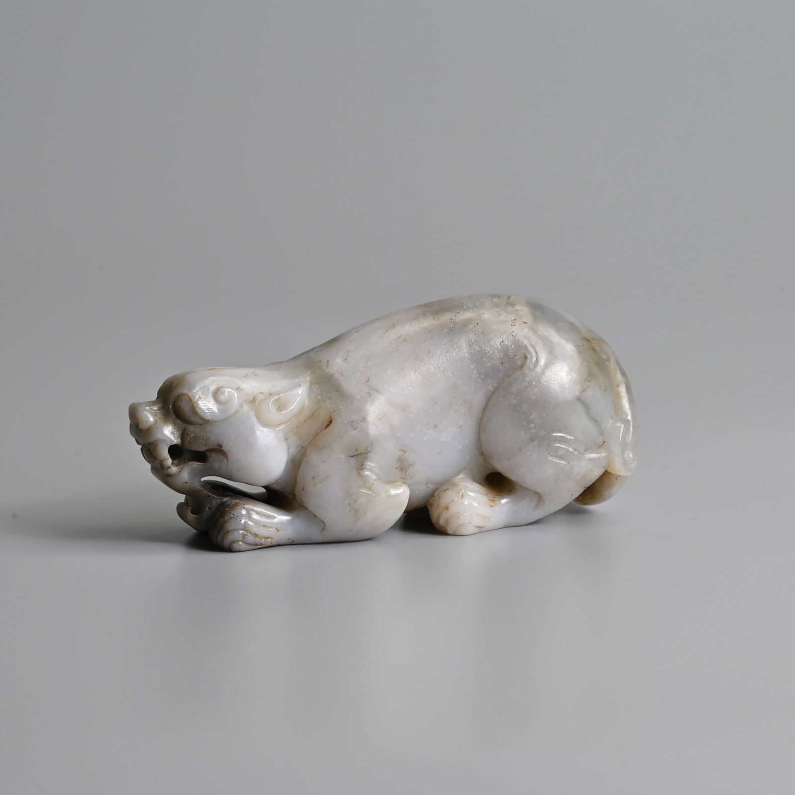 A CHINESE GREYISH JADE FIGURE OF A CROUCHING MYTHICAL BEAST. (1 of 7)