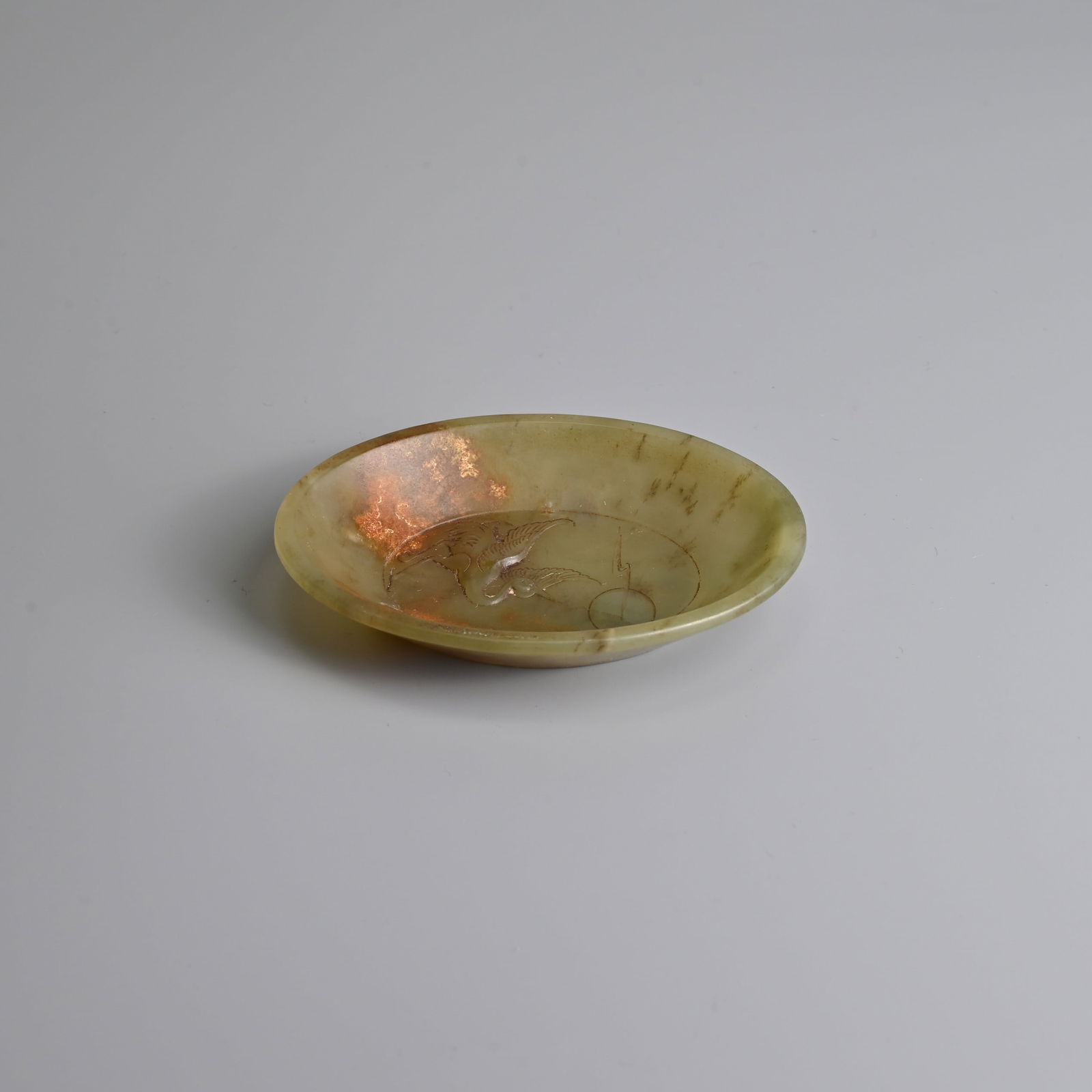 A CHINESE CARVED CELADON JADE BRUSH WASHER, QING DYNASTY.: A CHINESE CARVED CELADON JADE BRUSH WASHER, QING DYNASTY. Oval form dish carved in relief to the interior with a crane looking up at a moon with cloud. 9cm length. Condition: Patches of russet in plac