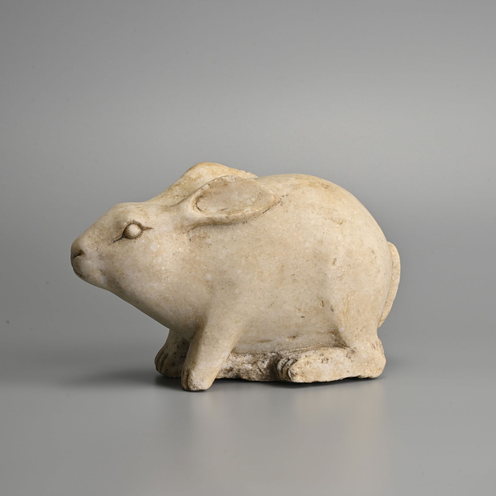 A CHINESE CARVED WHITE MARBLE RABBIT, POSSIBLY MING.: A CHINESE CARVED WHITE MARBLE RABBIT, POSSIBLY MING. Naturalistically modelled forward facing with its ears tucked back. 26cm length. Weight 5.5KG Provenance: Acquired in Hong Kong in the 1990s. Engli