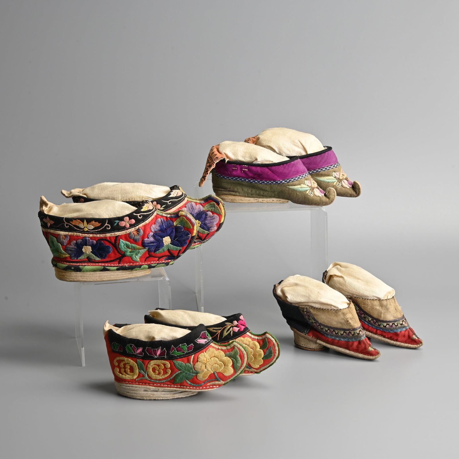 FOUR PAIRS OF CHINESE SILK EMBROIDERED COTTON LOTUS SHOES, QING DYNASTY/EARLY 20TH CENTURY.: FOUR PAIRS OF CHINESE SILK EMBROIDERED COTTON LOTUS SHOES, QING DYNASTY/EARLY 20TH CENTURY. Variously embroidered in brightly coloured silk threads with flowers, butterflies, scrolling tendrils and fo