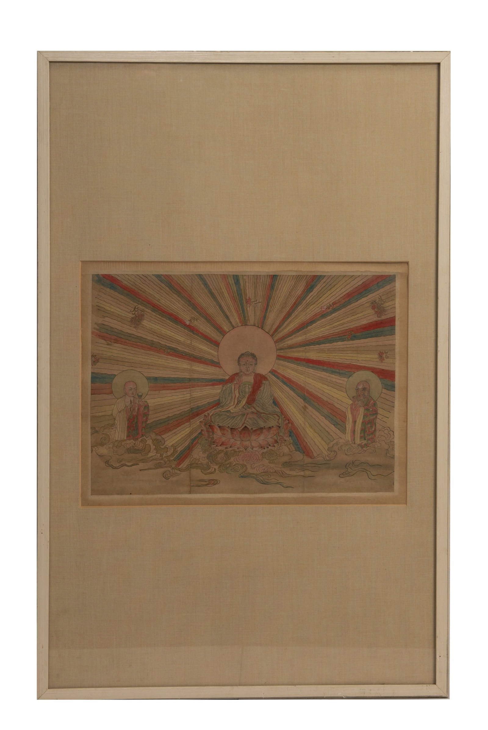 A FRAMED HAND COLOURED TIBETAN WOODBLOCK PRINT OF BUDDHA, EARLY 20TH CENTURY.: A FRAMED HAND COLOURED TIBETAN WOODBLOCK PRINT OF BUDDHA, EARLY 20TH CENTURY. On paper, featuring Buddha seated on a lotus flanked by attendants with mandorla above clouds and radiating lines with lot