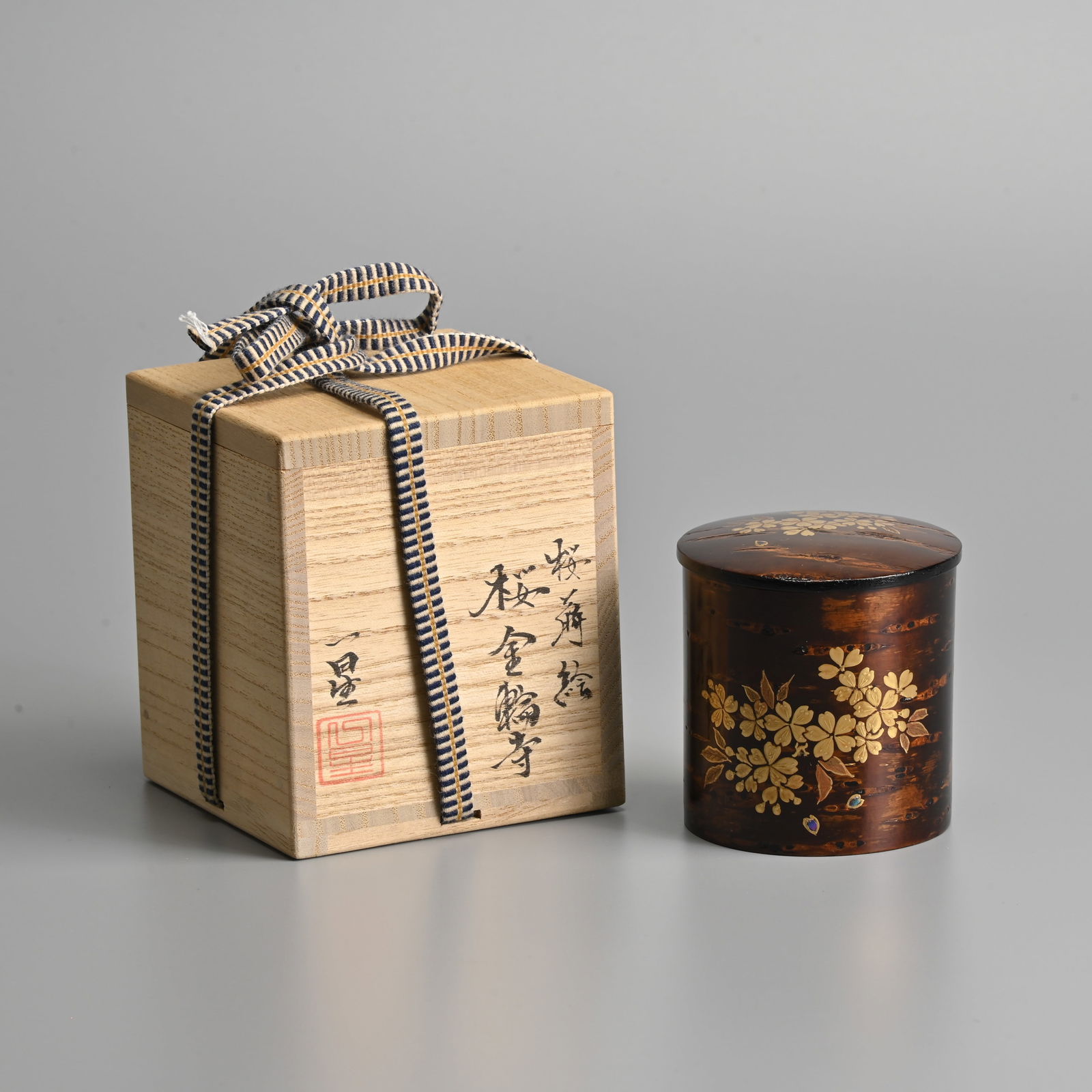 A JAPANESE LACQUER TEACADDY AND COVER (NATSUME) BY MINOWA ISSEI (B.1947).: A JAPANESE LACQUER TEACADDY AND COVER (NATSUME) BY MINOWA ISSEI (B.1947). Decorated with cherry blossoms on a ground of cherry blossom tree bark, fitted within the original box, 6.7cm high x 6.5cm dia