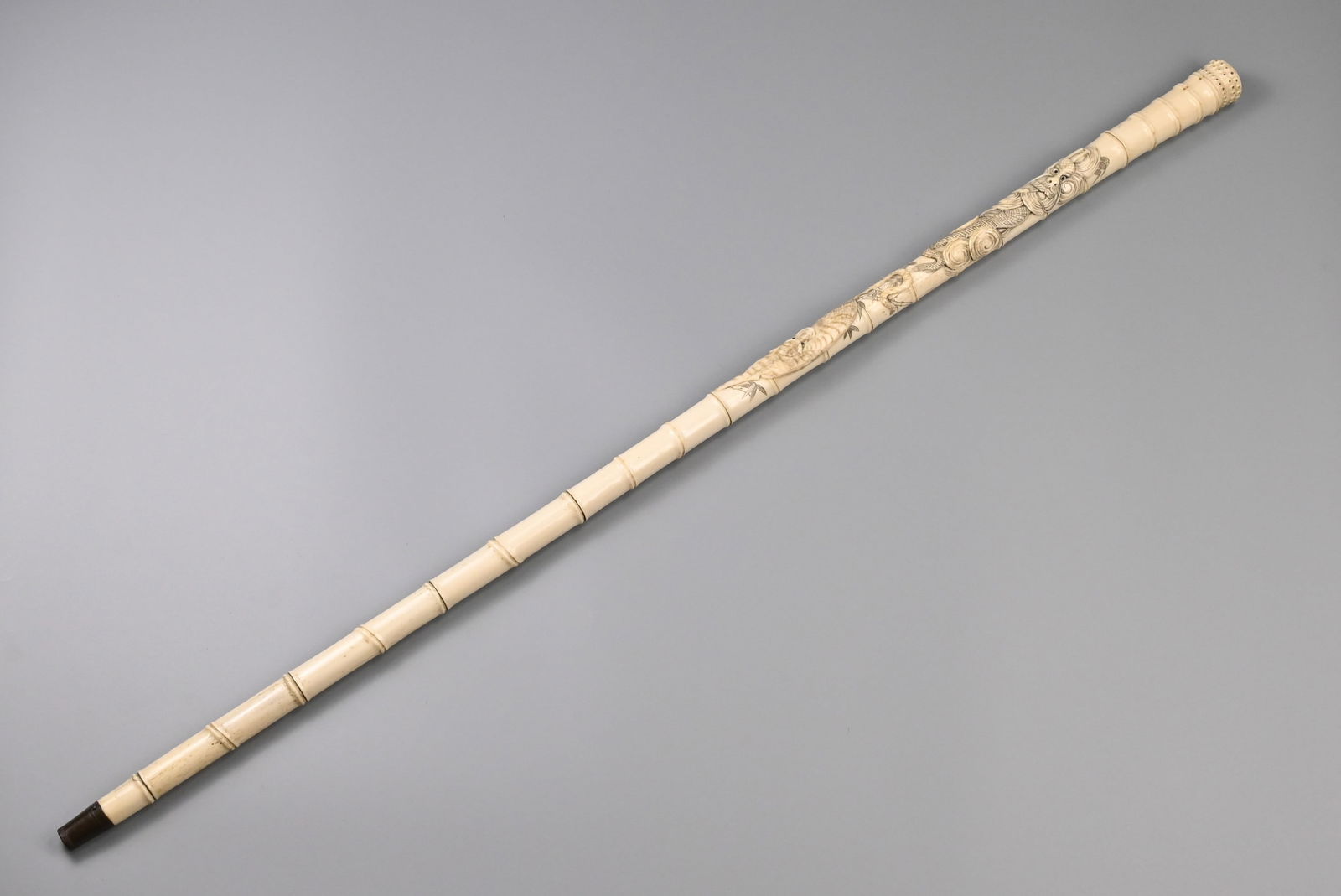 A JAPANESE CARVED SECTIONAL BONE WALKING CANE, LATE MEIJI PERIOD, 19/20TH CENTURY.: A JAPANESE CARVED SECTIONAL BONE WALKING CANE, LATE MEIJI PERIOD, 19/20TH CENTURY. Simulated bamboo cane tapering from the handle, carved in relief with a dragon amidst clouds and a tiger with incised