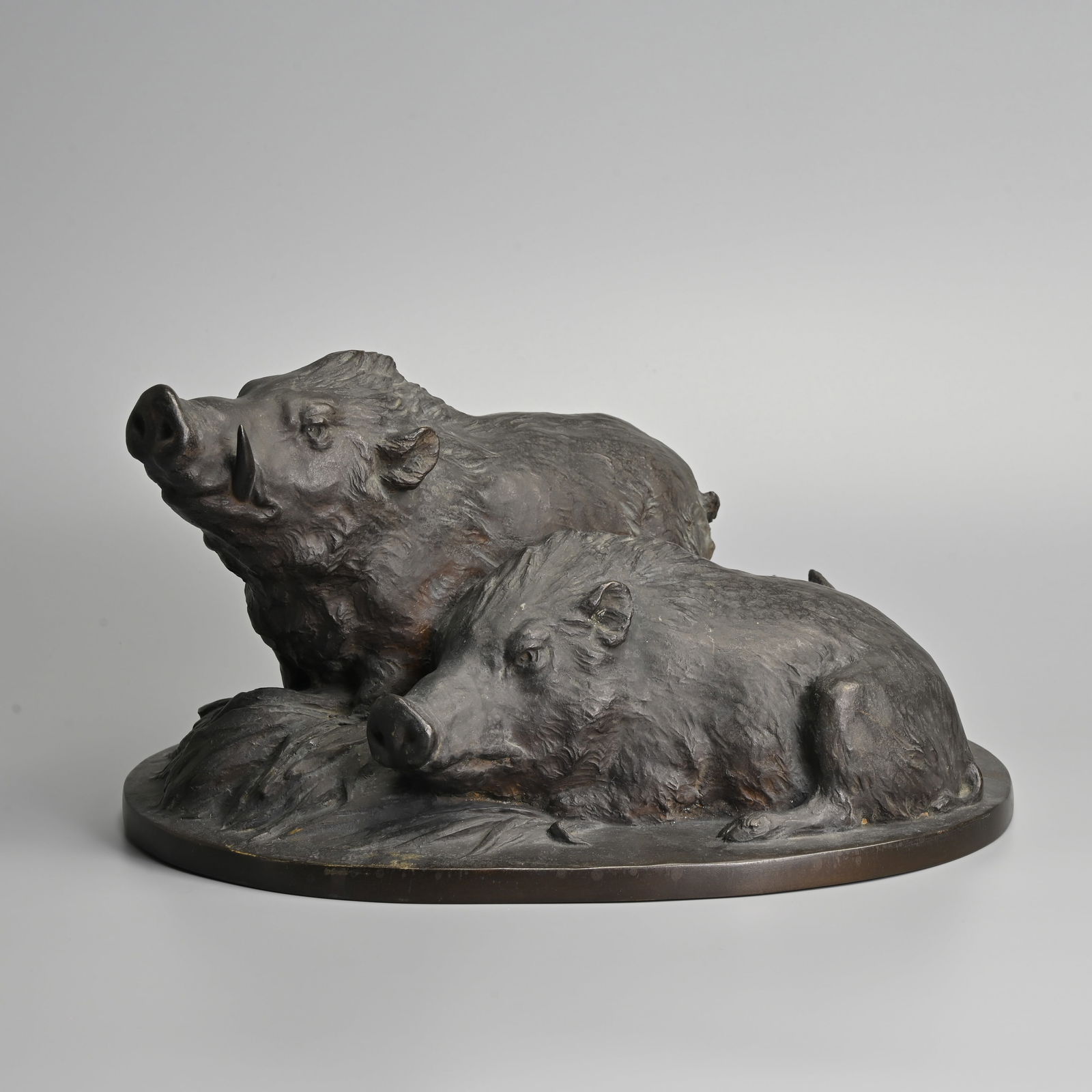 A JAPANESE BRONZE MODEL OF TWO BOARS BY SOGAN SAITO (1889-1974).: A JAPANESE BRONZE MODEL OF TWO BOARS BY SOGAN SAITO (1889-1974). Naturalistically modelled, side-by-side on a grassy reeded oval base, signed to reverse of base, 21cm high x 65cm wide x 25cm deep, wei