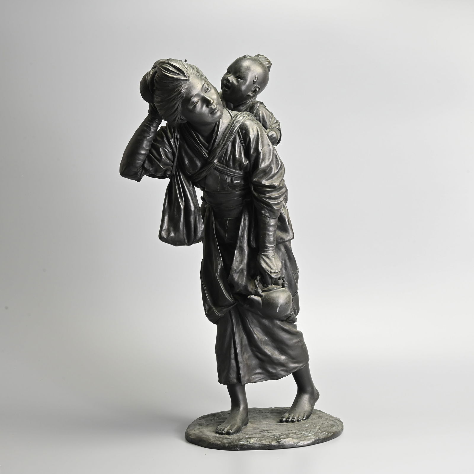 A VERY LARGE JAPANESE BRONZE GROUP OF A MOTHER AND CHILD, TOKYO SCHOOL, 20TH CENTURY.: A VERY LARGE JAPANESE BRONZE GROUP OF A MOTHER AND CHILD, TOKYO SCHOOL, 20TH CENTURY. The young mother walking with her child tied to her back, carrying a kettle, the child reaching for her hair pin,