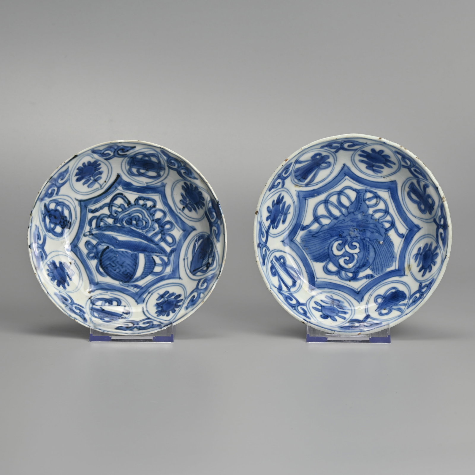 A MATCHED PAIR OF CHINESE PORCELAIN BLUE AND WHITE SAUCERS, LATE MING DYNASTY, WANLI PERIOD: Each painted with a ball, leaves and scrollwork within a star shaped cartouche, the border with scrolls and flowers within circular cartouches, the undersides with foliate panels, approx. 14 cm diam. 