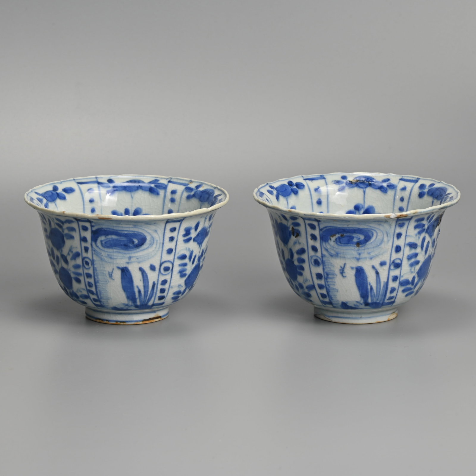 A MATCHED PAIR OF CHINESE KRAAK PORCELAIN BLUE AND WHITE CROW BOWLS, LATE MING DYNASTY, WANLI PERIOD: Each with flared rim, painted with a crow before plants in landscape alternating with panels of flowers, approx. 13 cm diam. (2) Provenance: Private collection, Japan.