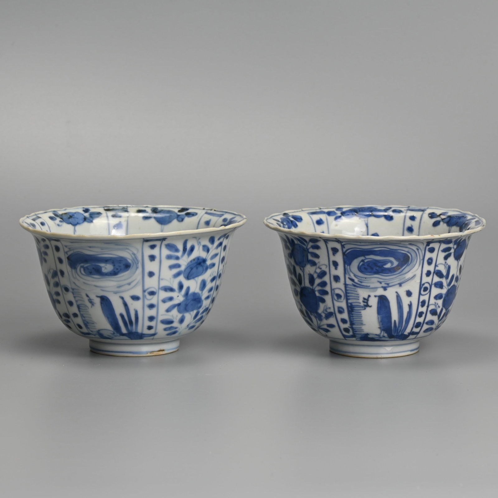 A MATCHED PAIR OF CHINESE KRAAK PORCELAIN BLUE AND WHITE CROW BOWLS, LATE MING DYNASTY, WANLI PERIOD: Each with flared rim, painted with a crow before plants in landscape alternating with panels of flowers and bamboo, approx. 13 cm diam. (2) Provenance: Private collection, Japan.