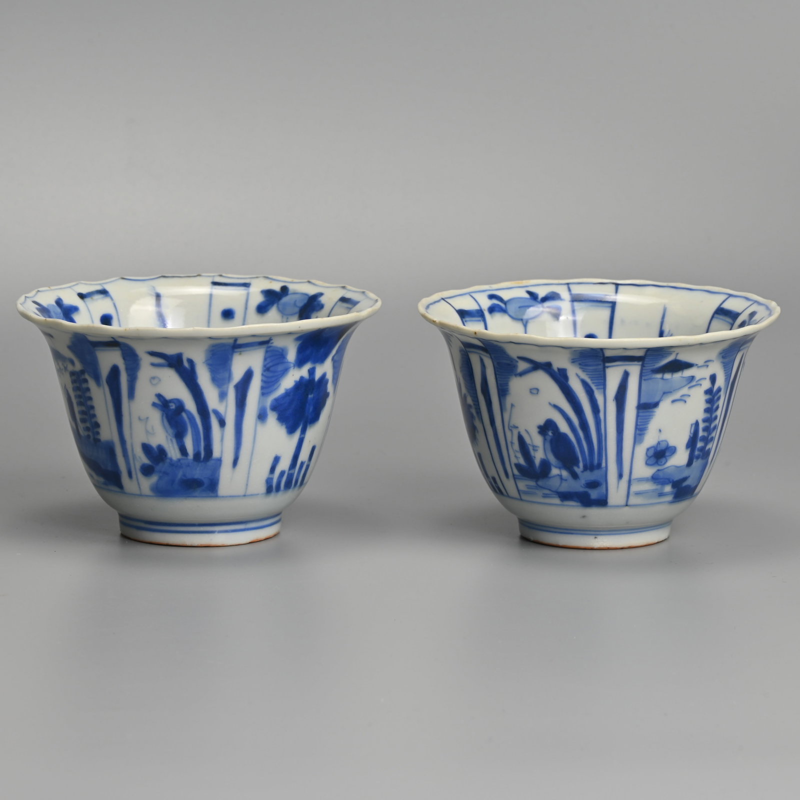 A MATCHED PAIR OF CHINESE KRAAK PORCELAIN BLUE AND WHITE CROW BOWLS, LATE MING DYNASTY, WANLI PERIOD: Each with flared rim, the interior painted with a crow before plants in landscape, within panels of tall plants and fruiting plants, the exterior with alternating panels of flowers, figures before pav