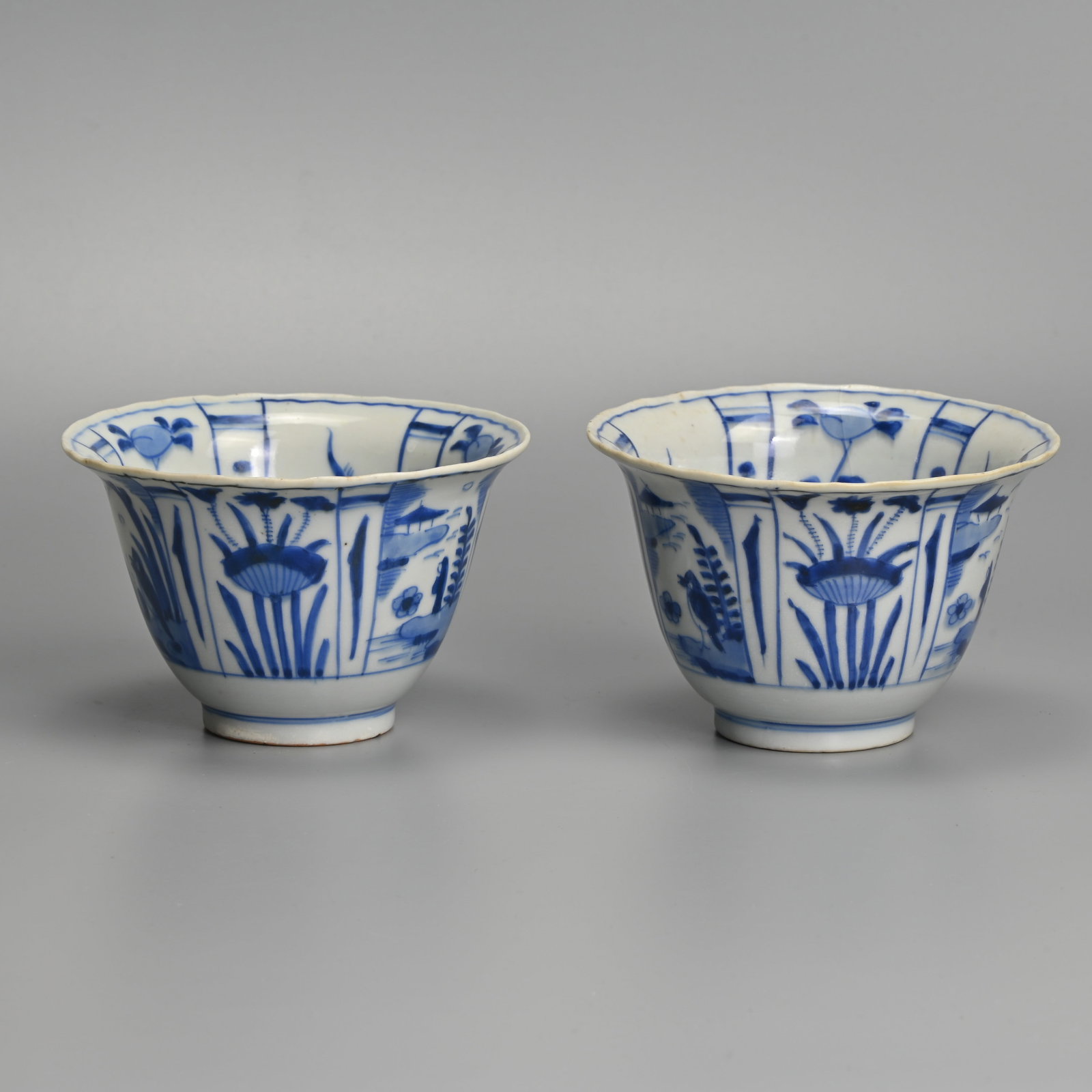 A MATCHED PAIR OF CHINESE KRAAK PORCELAIN BLUE AND WHITE CROW BOWLS, LATE MING DYNASTY, WANLI PERIOD: Each with flared rim, the interior painted with a crow before plants in landscape, within panels of tall plants and fruiting plants, the exterior with alternating panels of flowers, figures before pav