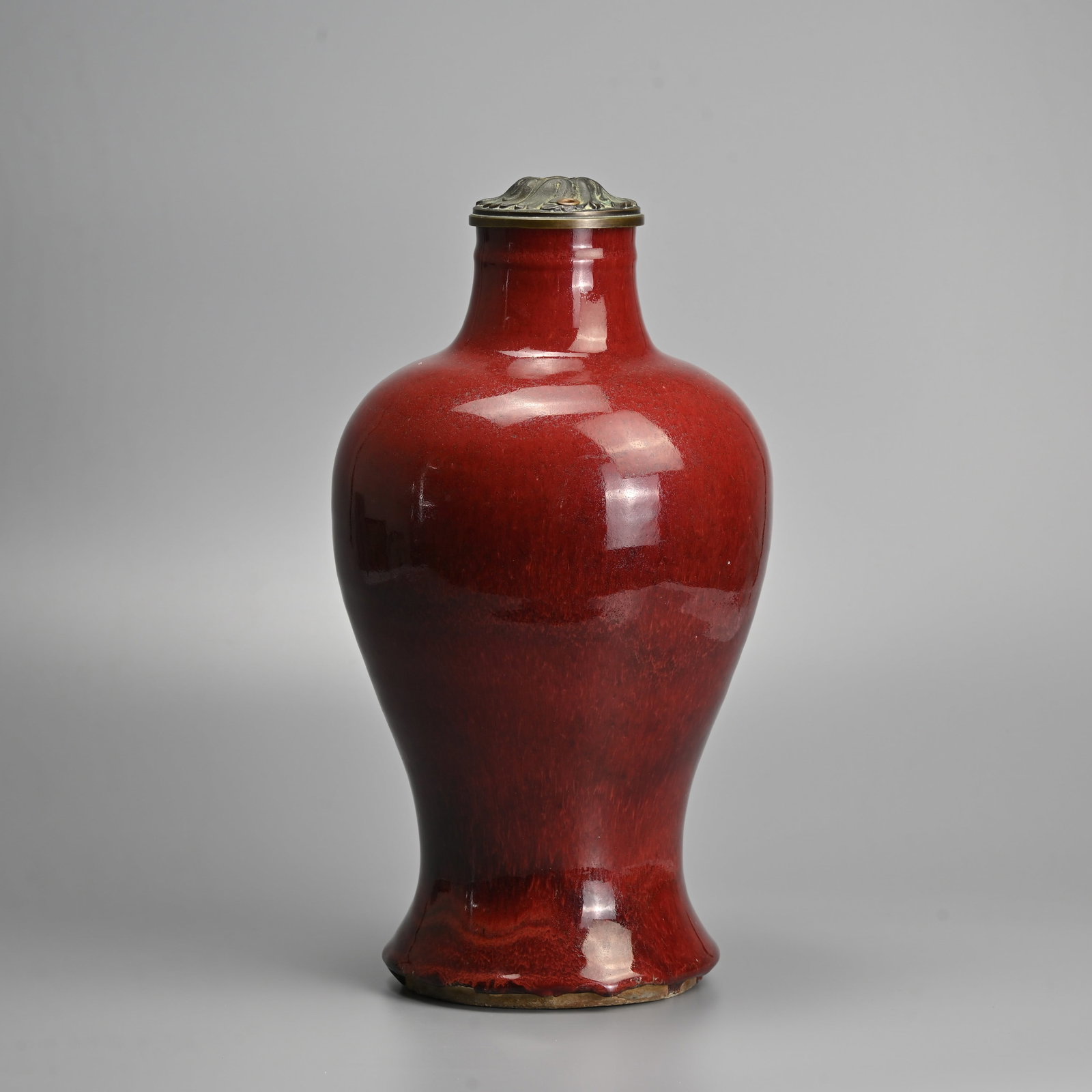 A CHINESE SANG DE BOEUF GLAZED PORCELAIN VASE, 18/19TH CENTURY.: Of baluster form covered in a rich deep red mottled glaze, with a later metal mount to the rim. 36.5cm tall.