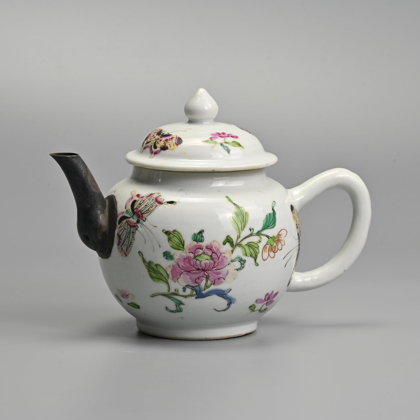 A CHINESE FAMILLE ROSE PORCELAIN TEA POT, QING DYNASTY.: Decorated with butterflies and peony sprays in colourful enamels, with a replacement metal spout. 18.5cm length.