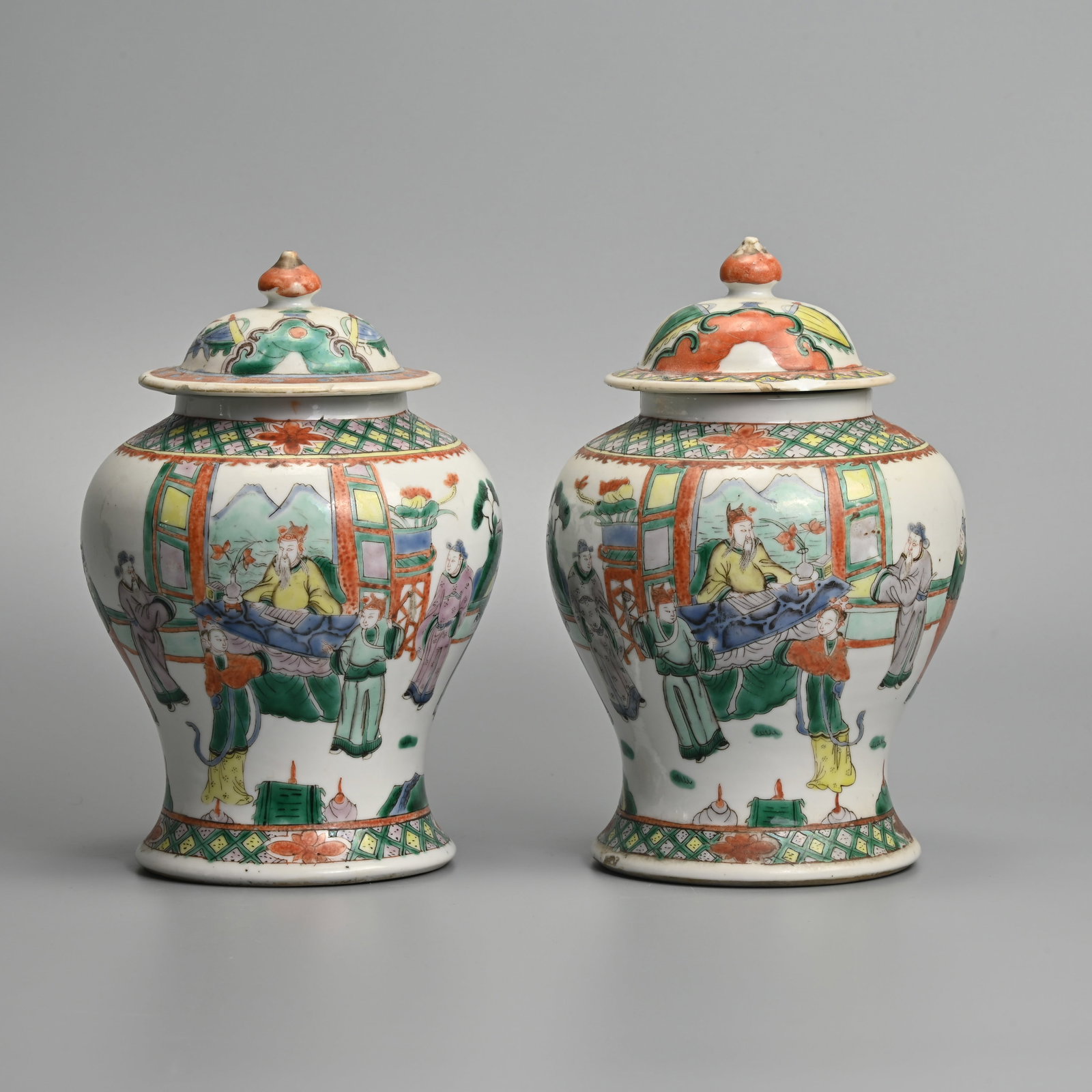 A MIRRORED PAIR OF CHINESE FAMILLE VERTE PORCELAIN JARS AND COVERS, LATE QING DYNASTY.: Decorated with various scholars or dignitaries. Each with four character Kangxi mark to base in underglaze blue. 21.5cm tall including cover. (2).
