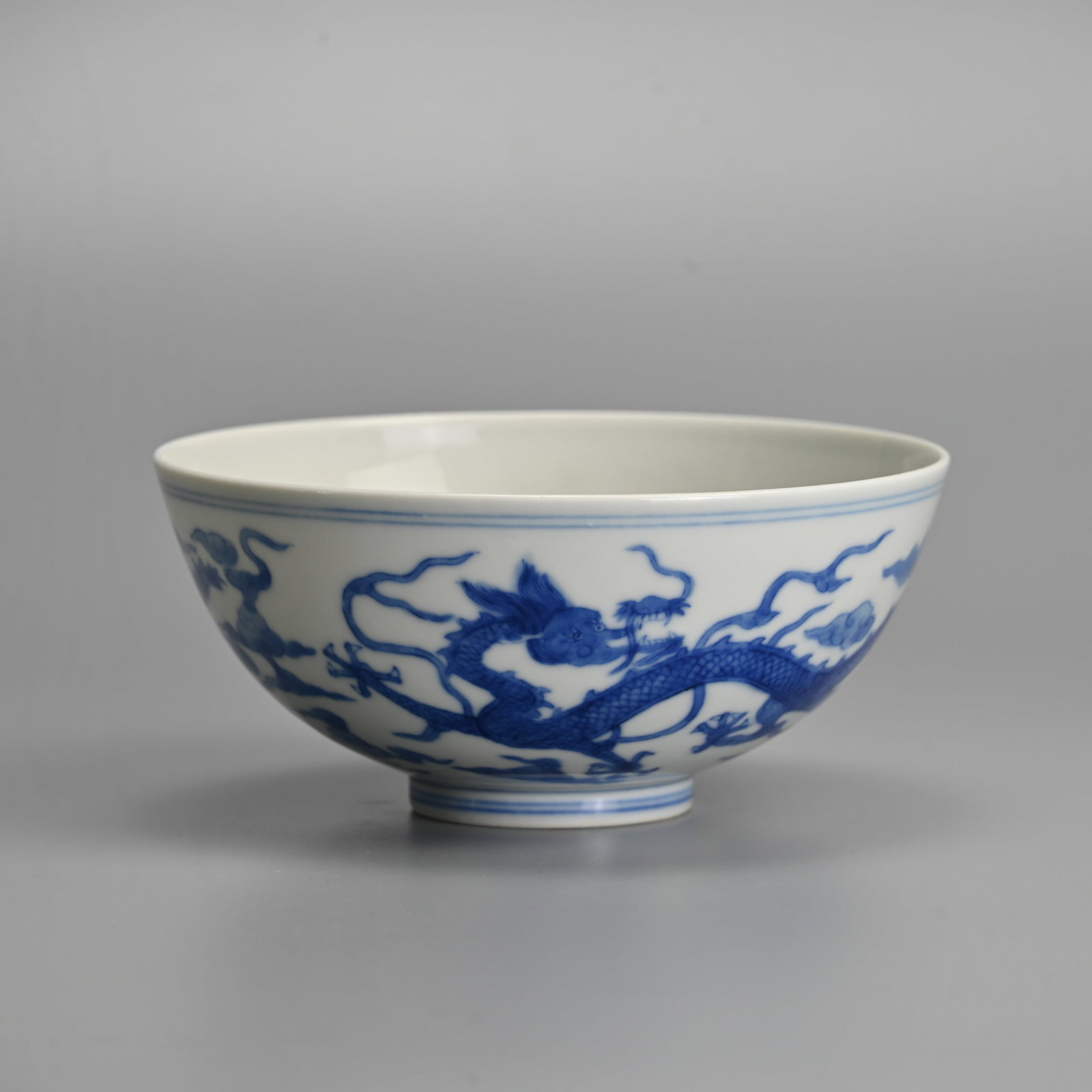 A CHINESE BLUE AND WHITE PORCELAIN 'DRAGON' BOWL, GUANGXU MARK.: Decorated with dragons in flight amidst ruyi cloud scrolls. A third dragon in a roundel to the interior. Six character mark of Guangxu to base in underglaze blue. 14.3cm diam.