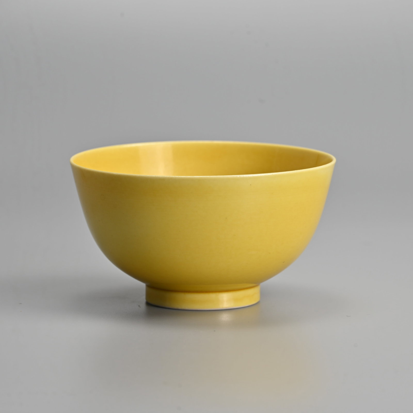 A CHINESE YELLOW GLAZED PORCELAIN BOWL, GUANGXU MARK.: Rounded body raised on a short foot covered in a yellow glaze with six character mark of Guangxi in underglaze blue. 10.3cm diam.