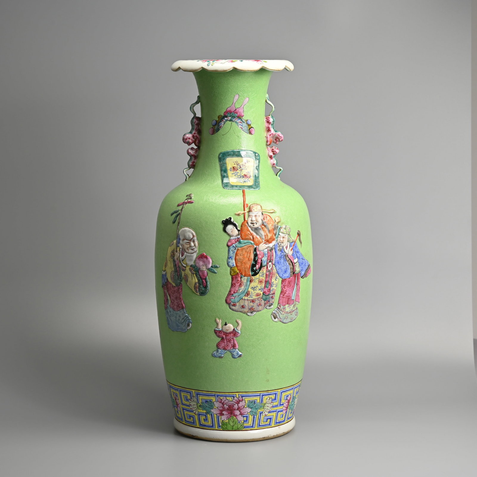 A LARGE CHINESE FAMILLE ROSE LIME GREEN SGRAFFITO GROUND PORCELAIN 'SANXING AND MAGU' BALUSTER VASE.: Tall vase with lion handles and moulded decoration featuring the 'Three Star Gods', Sanxing in low relief. To verso a figure of the Daoist immortal 'Magu' and butterflies. All reserved on a sgraffito 