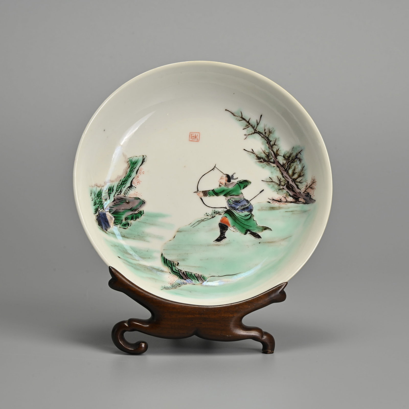 A CHINESE FAMILLE VERTE PORCELAIN 'ARCHER' DISH WITH WOODEN STAND, 19TH CENTURY, QING DYNASTY.: A CHINESE FAMILLE VERTE PORCELAIN 'ARCHER' DISH WITH WOODEN STAND, 19TH CENTURY, QING DYNASTY. Decorated with a male archer firing an arrow. A two character seal mark in iron red to the front reading 