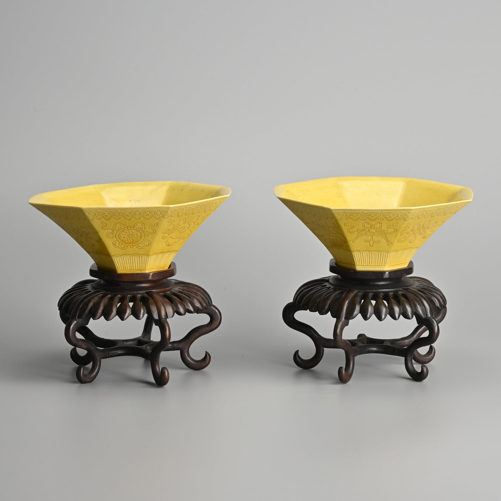 A PAIR OF CHINESE YELLOW GLAZED INCISED 'BAJIXIANG' OCTAGONAL PORCELAIN BOWLS ON STANDS, KANGXI: A PAIR OF CHINESE YELLOW GLAZED INCISED 'BAJIXIANG' OCTAGONAL PORCELAIN BOWLS ON STANDS, KANGXI MARK, LATE QING DYNASTY. Decorated with the Eight Buddhist emblems with ruyi heads to the rim, covered i