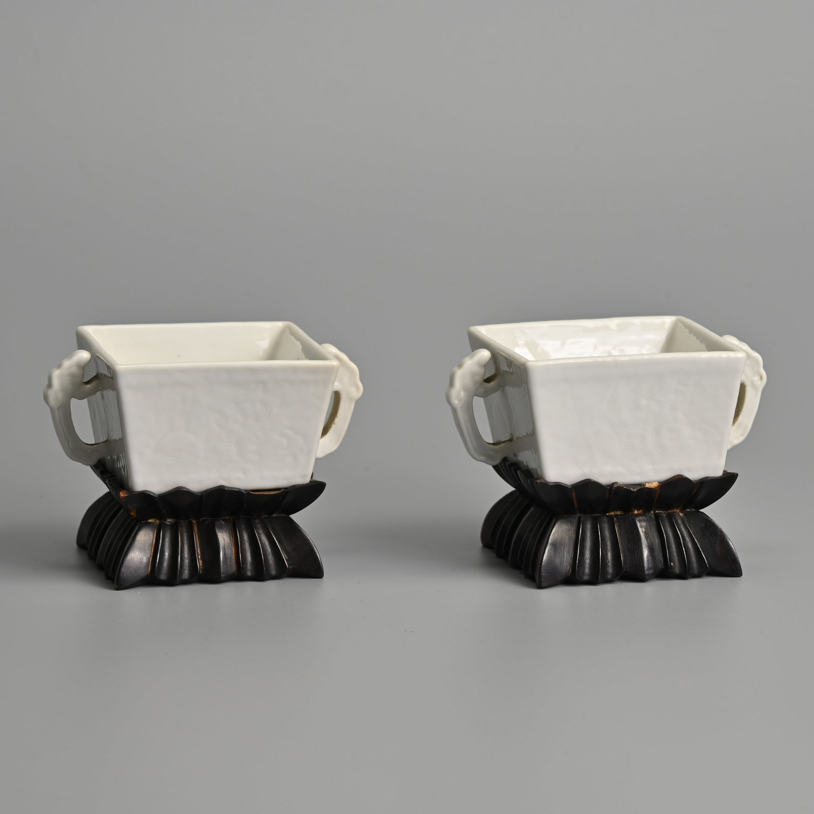 A RARE PAIR OF CHINESE WHITE GLAZED ANHUA DECORATED PORCELAIN SQUARE FORM TWIN HANDLED 'DRAGON': A RARE PAIR OF CHINESE WHITE GLAZED ANHUA DECORATED PORCELAIN SQUARE FORM TWIN HANDLED 'DRAGON' CUPS, KANGXI YUZHI MARKS, QING DYNASTY. Each side of the cup matching in decoration, featuring a dragon 