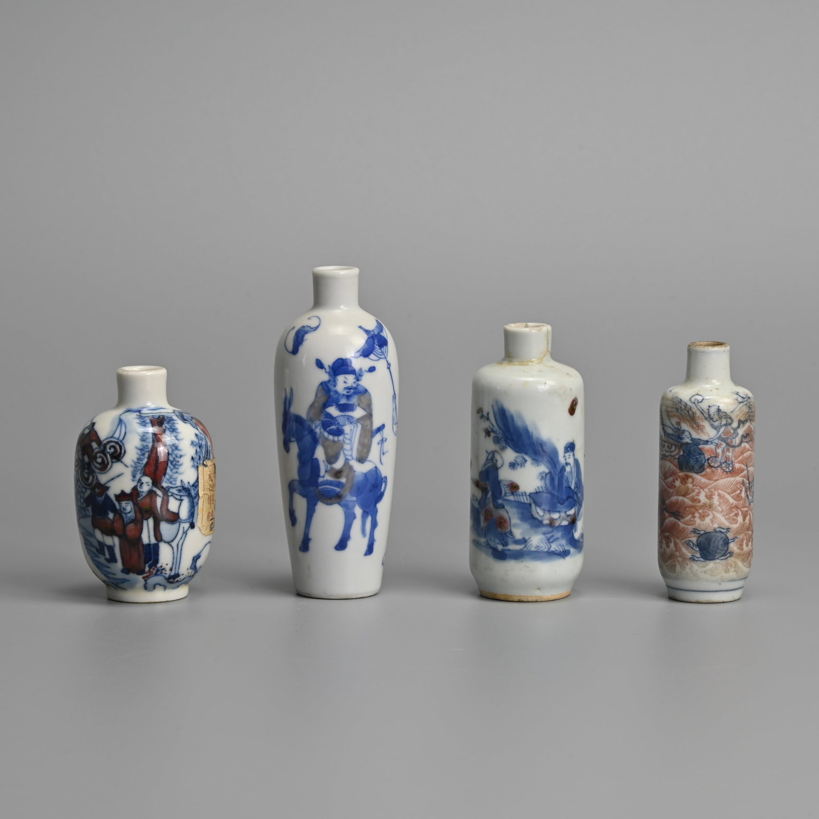 FOUR CHINESE UNDERGLAZE BLUE AND COPPER RED PORCELAIN SNUFF BOTTLES, 19/20TH CENTURY.: FOUR CHINESE UNDERGLAZE BLUE AND COPPER RED PORCELAIN SNUFF BOTTLES, 19/20TH CENTURY. Of various forms decorated with figural scenes. The largest bottle with four character Qianlong to base in undergl