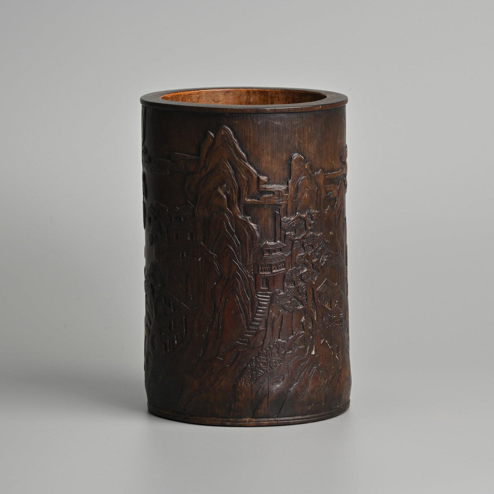 A CHINESE CARVED AND INSCRIBED BAMBOO BRUSH POT, 'BITONG', AFTER ZHENG QIAN (691-759), 18/19TH: A CHINESE CARVED AND INSCRIBED BAMBOO BRUSH POT, 'BITONG', AFTER ZHENG QIAN (691-759), 18/19TH CENTURY. Of cylindrical form carved in shallow relief with a mountainous landscape with buildings and tre