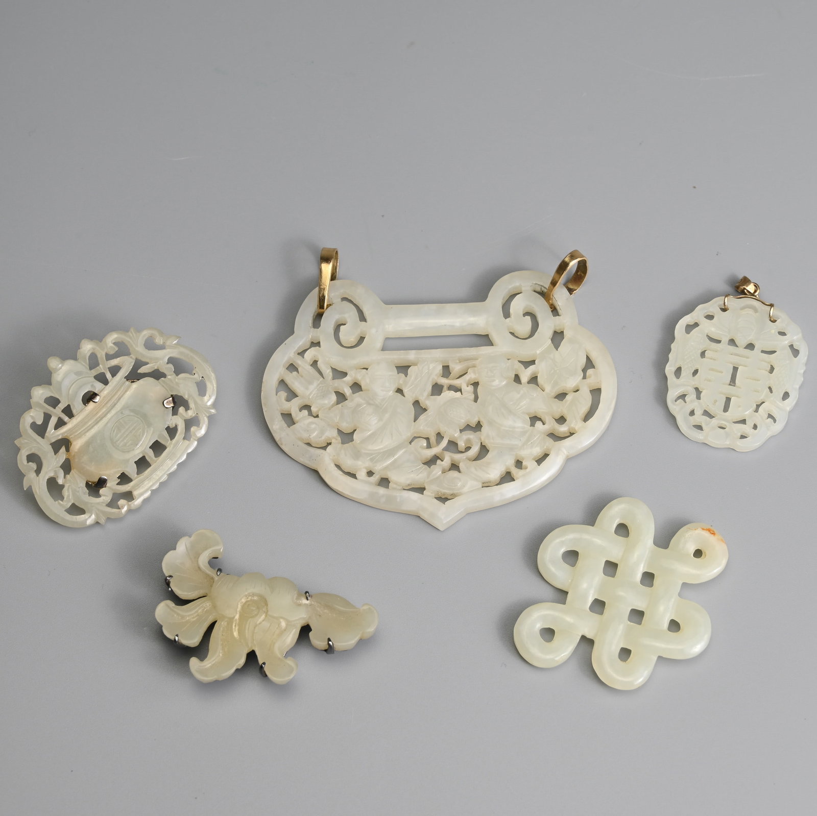 A GROUP OF CHINESE WHITE AND PALE CELADON JADE ITEMS, 19/20TH CENTURY.: A GROUP OF CHINESE WHITE AND PALE CELADON JADE ITEMS, 19/20TH CENTURY. To include a carved and pierced ruyi form pendant featuring two boys and floral scrolls, with two metal loops; A pierced brooch f