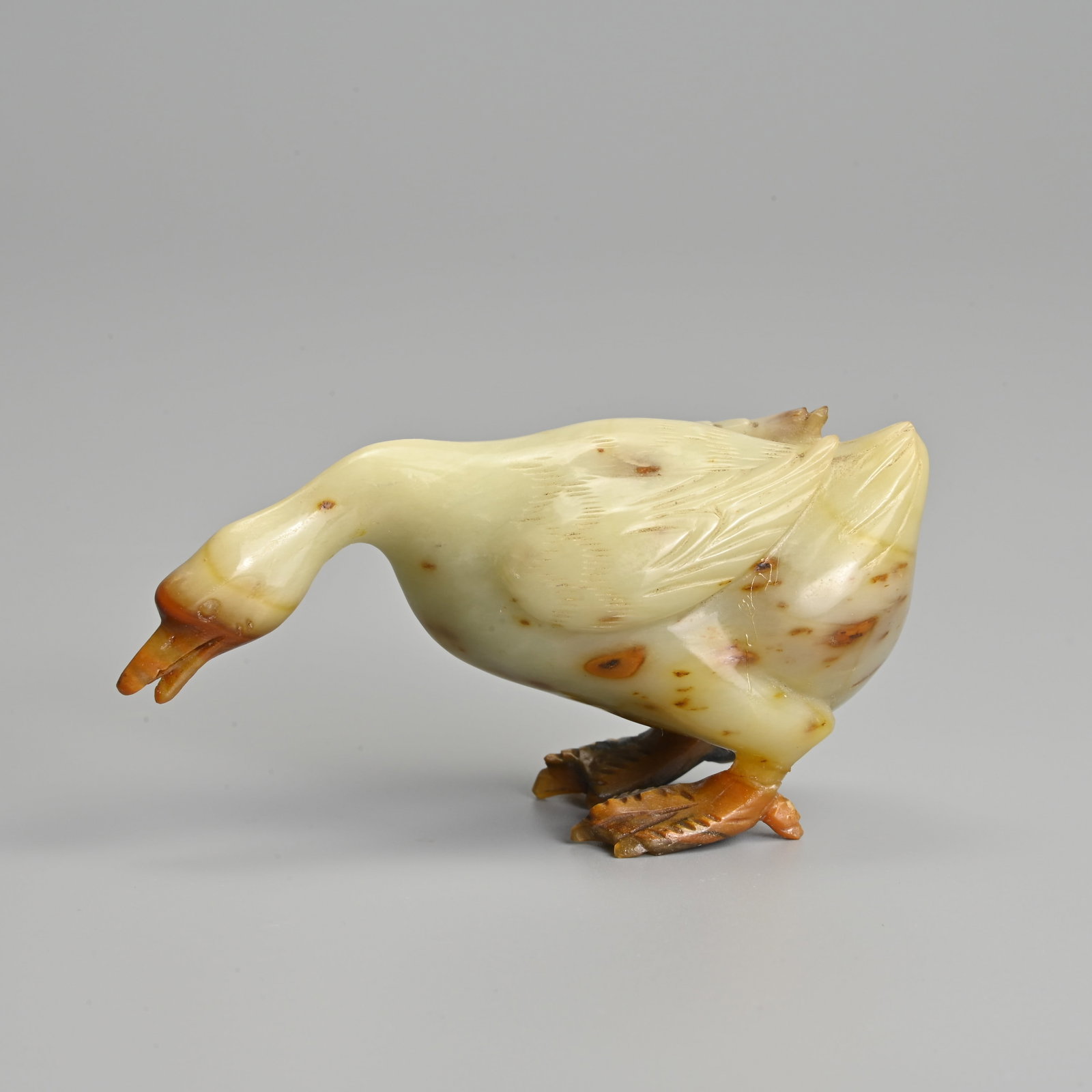 A CHINESE CELADON AND RUSSET JADE CARVING OF A GOOSE, QING DYNASTY. (1 of 6)