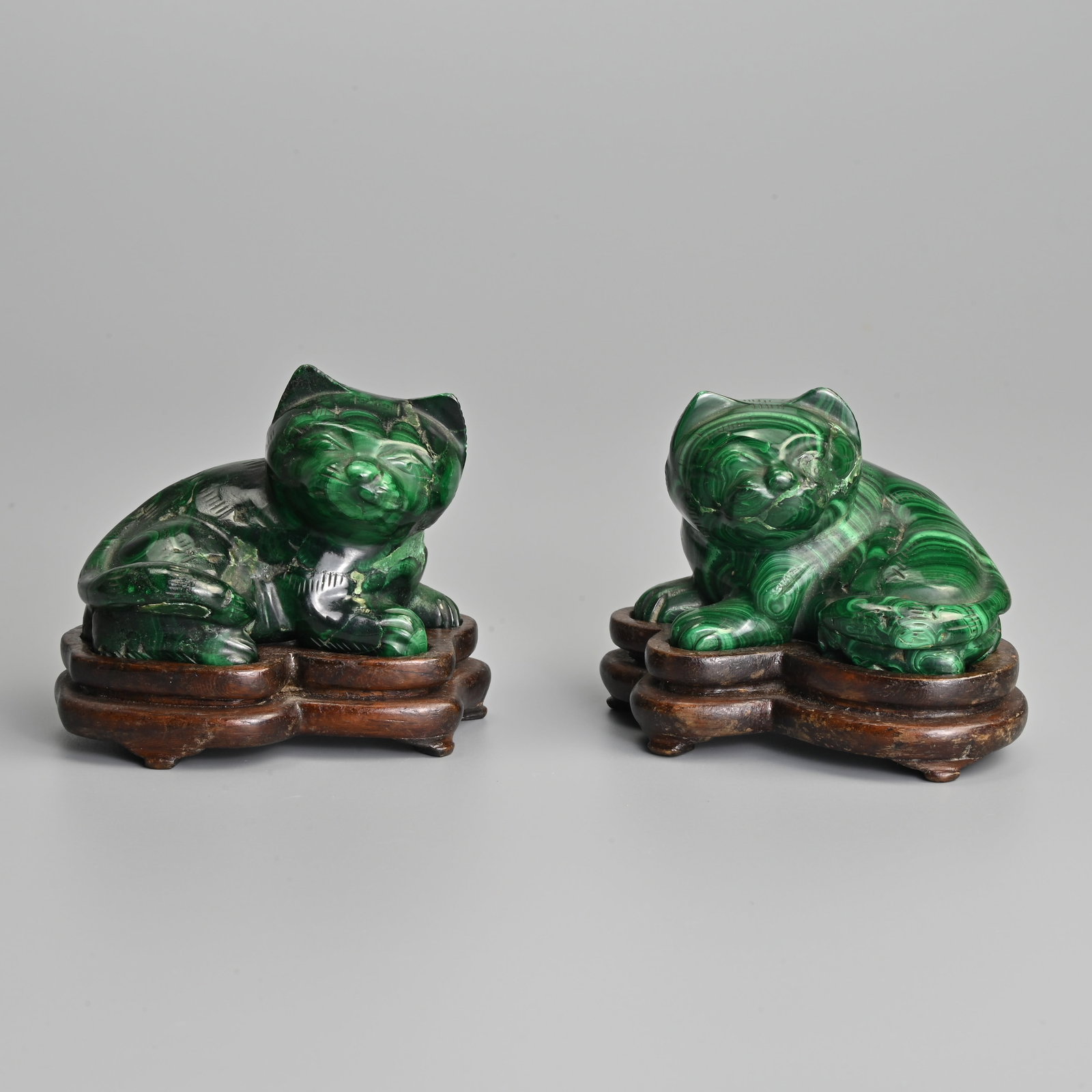 A PAIR OF CHINESE CARVED MALACHITE FIGURES OF RECUMBENT CATS ON WOODEN STANDS. (1 of 10)